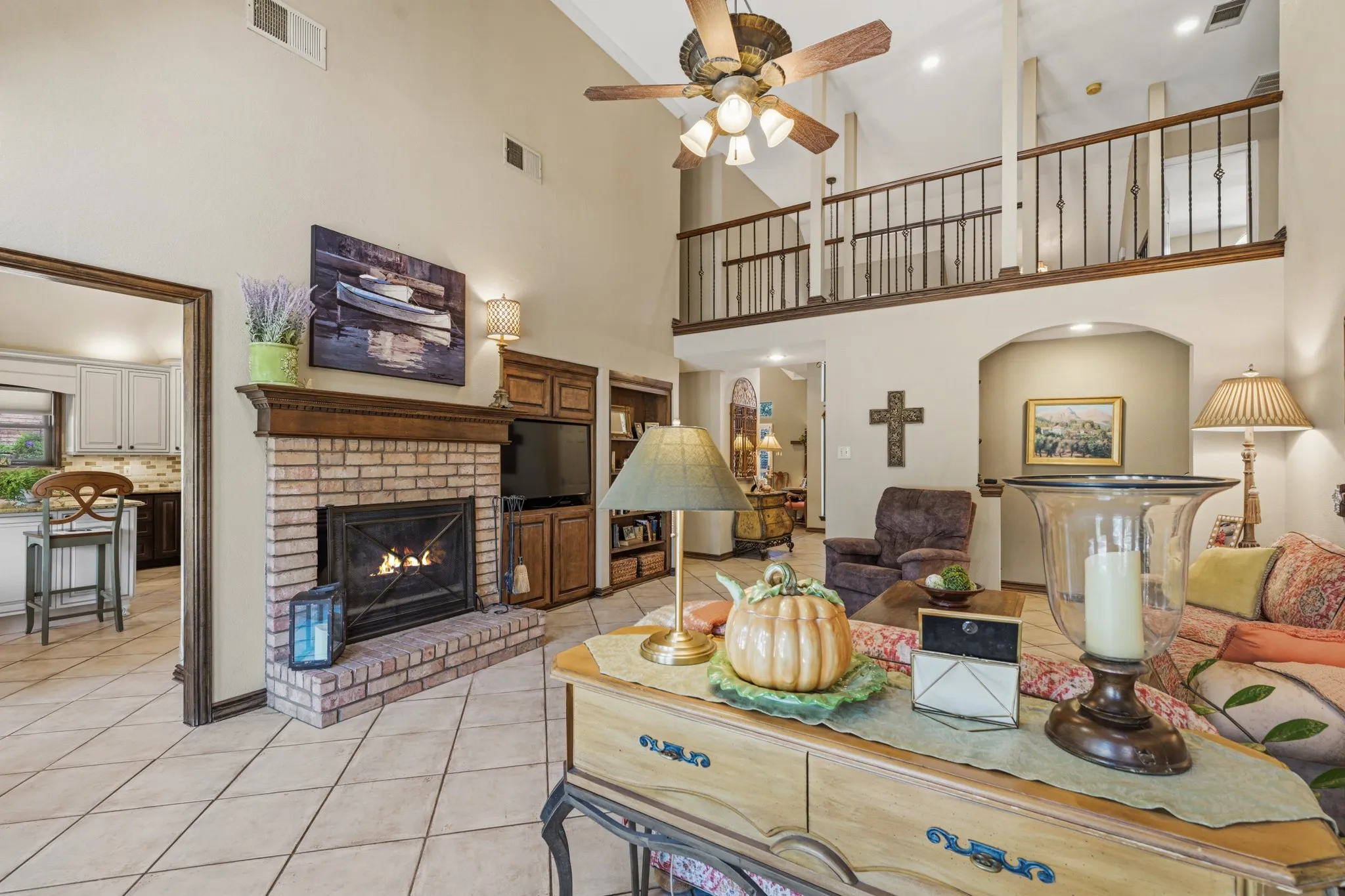 Large ceramic tile flooring, a cozy brick fireplace, and expansive windows and glass doors overlooking the backyard create a warm and inviting atmosphere.