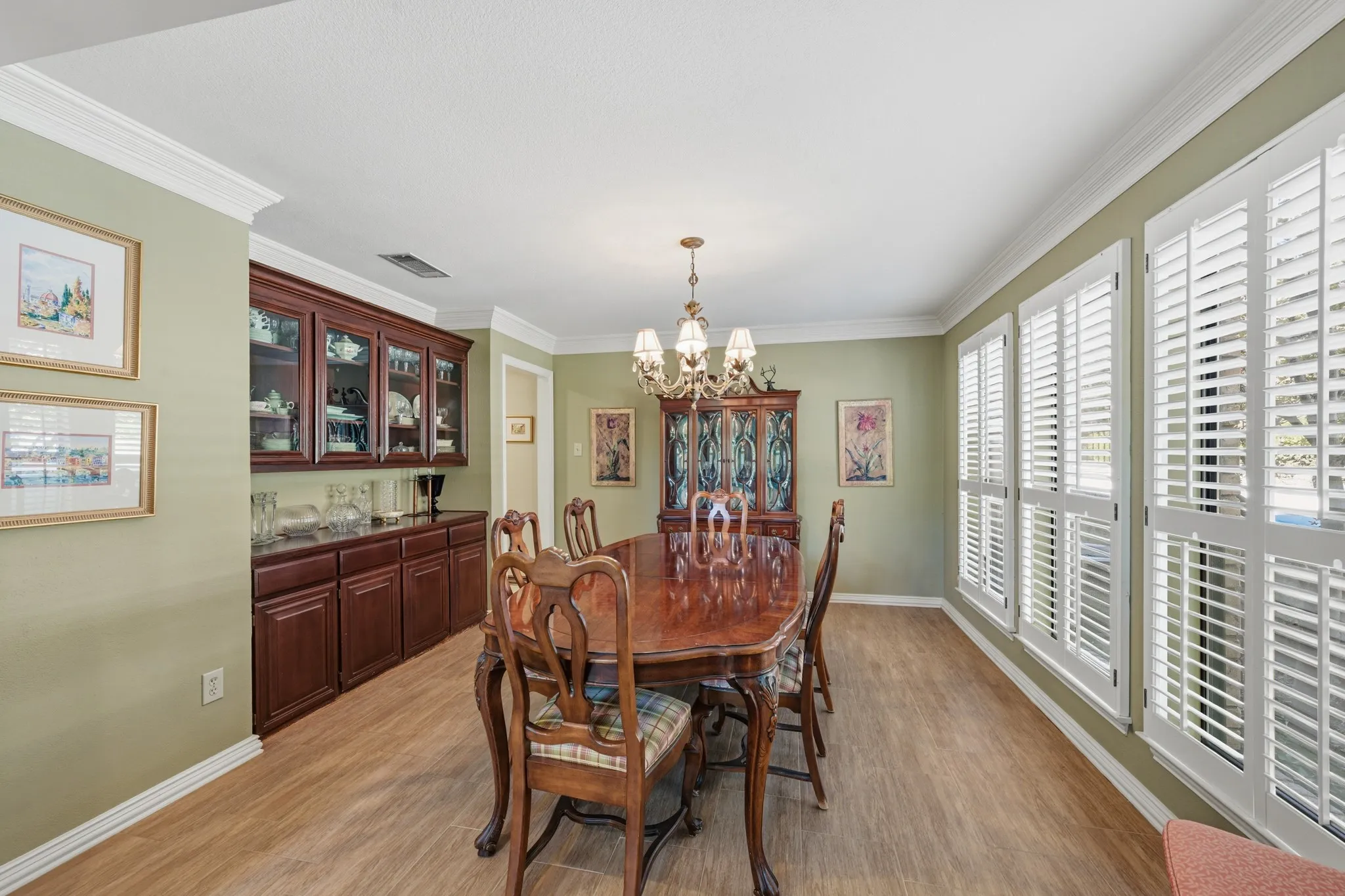 Elegant formal dining room featuring rich wood cabinetry with glass-front display cabinets, and a classic chandelier.