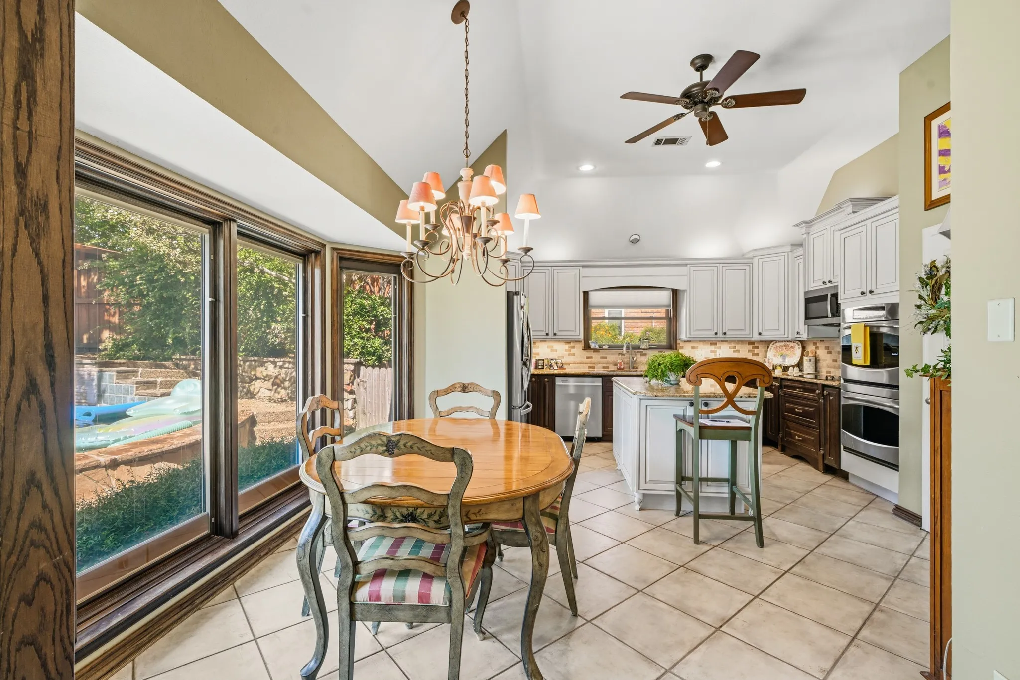  A charming chandelier adds warmth, while ceramic tile flooring and neutral finishes complement the adjoining kitchen.