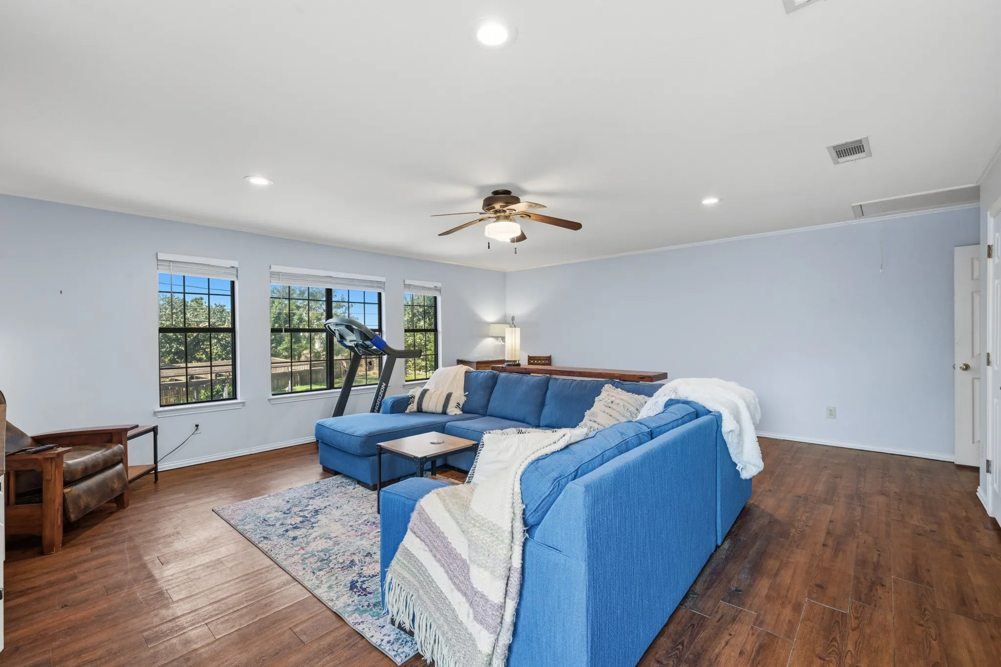 The spacious layout accommodates comfortable seating, a TV area, and additional space for recreation or relaxation. A ceiling fan and recessed lighting complete this inviting space, perfect for entertaining, movie nights, or enjoying a private retreat upstairs.