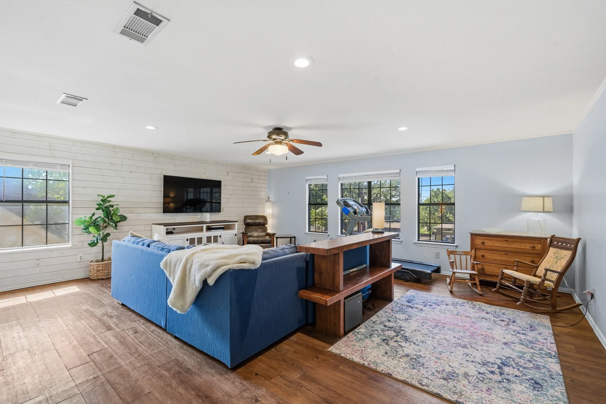 Versatile upstairs bonus room offering endless possibilities for a media room, game room, or secondary living area. Featuring warm wood-look flooring, a stylish white shiplap accent wall, and abundant natural light from multiple windows.