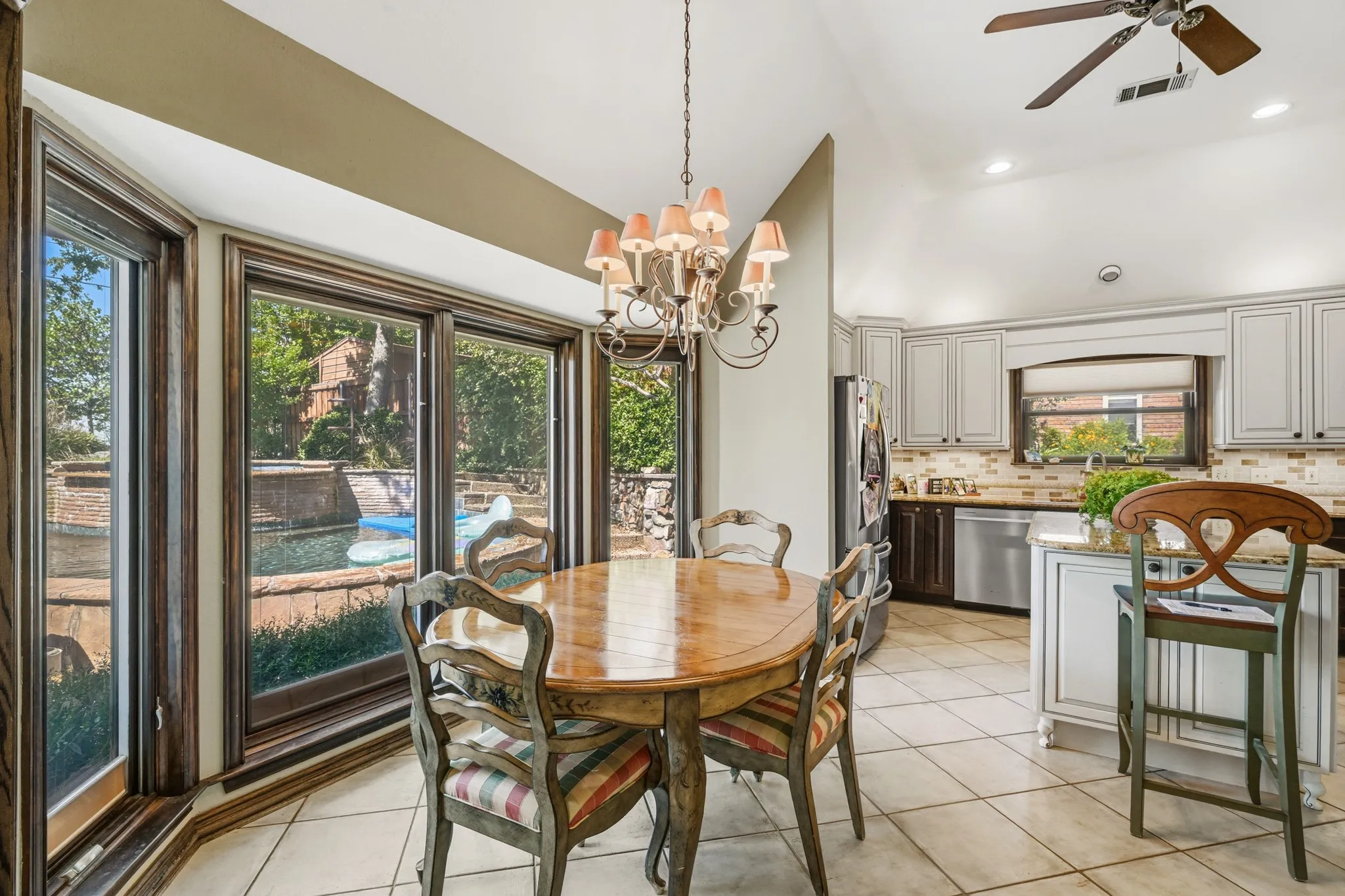 Bright and inviting breakfast nook featuring expansive windows overlooking the backyard and sparkling swimming pool.