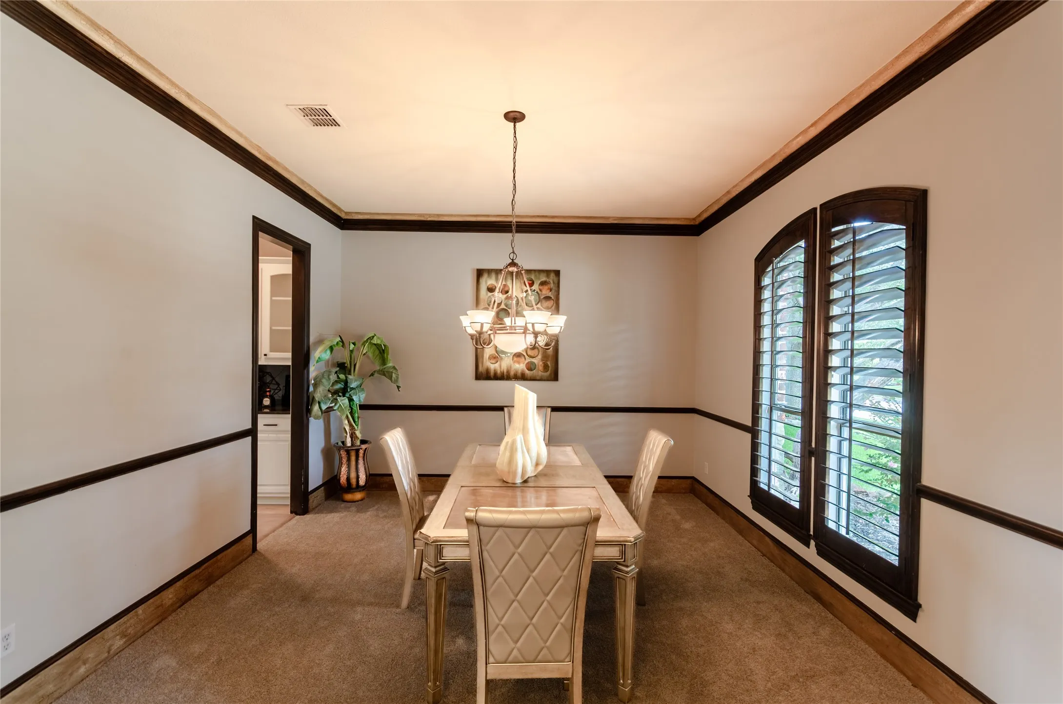 Formal room featuring dark wood crown molding, chair rail trim, and window casings