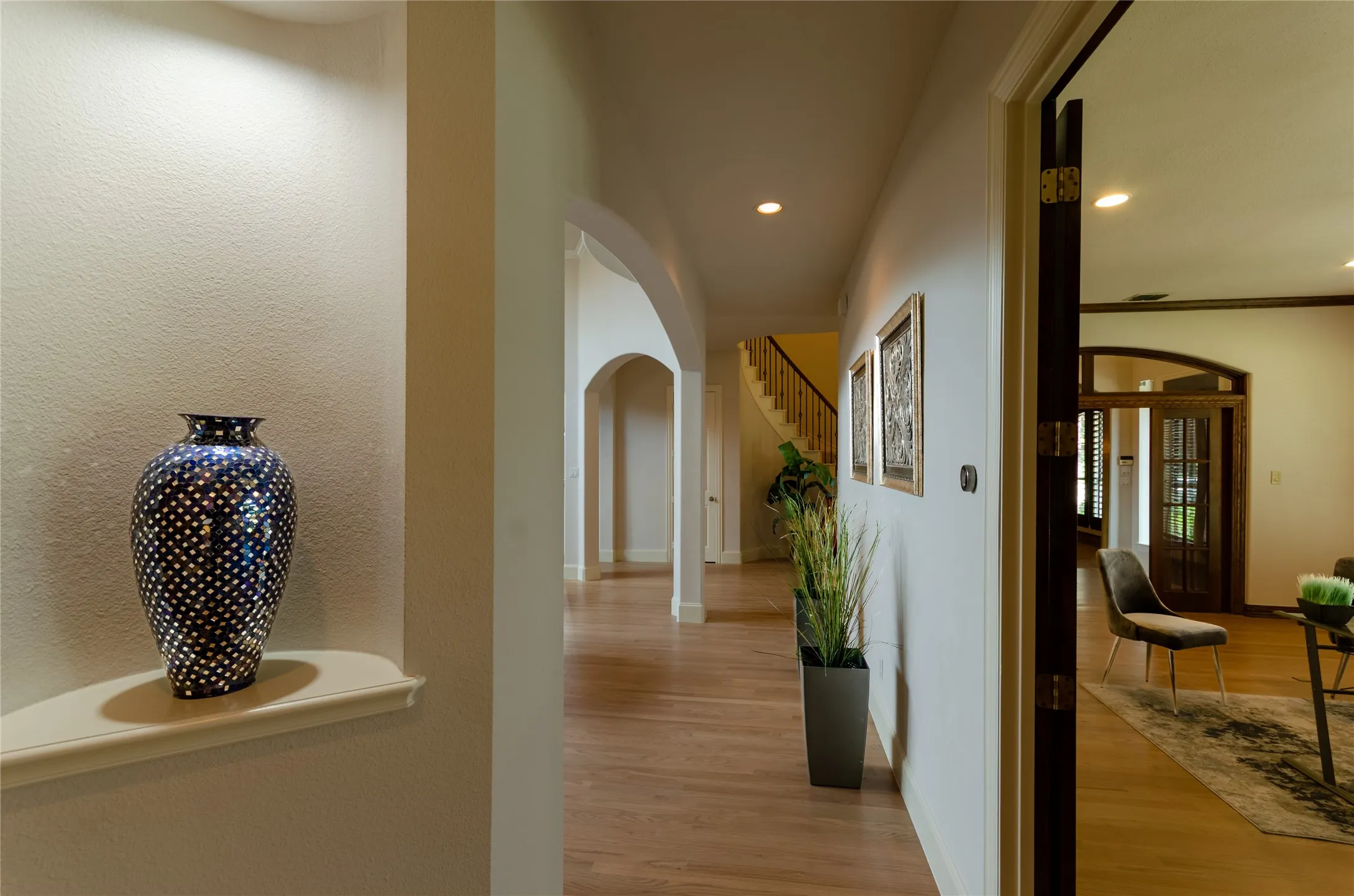 Interior architecture featuring recessed wall niches, arched entryways, wood-finish flooring, and recessed ceiling lighting