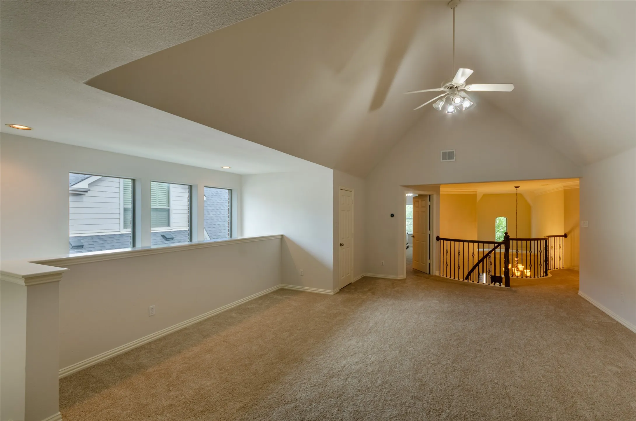 Game room Vaulted ceiling, ceiling fan with integrated lighting, recessed lighting, and wooden staircase railing