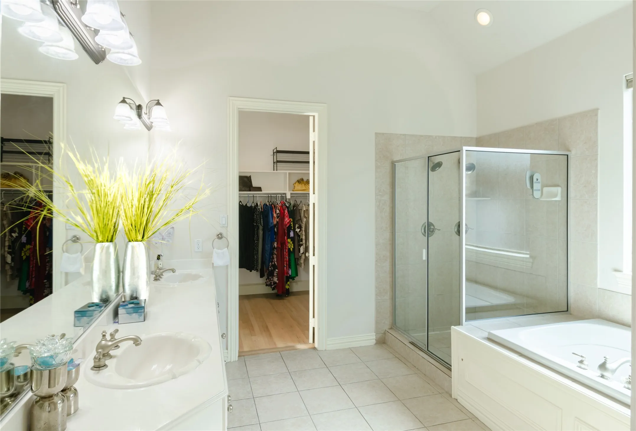 Double vanity with a solid-surface countertop, walk-in shower with a glass enclosure, built-in soaking tub, and ceramic tile flooring