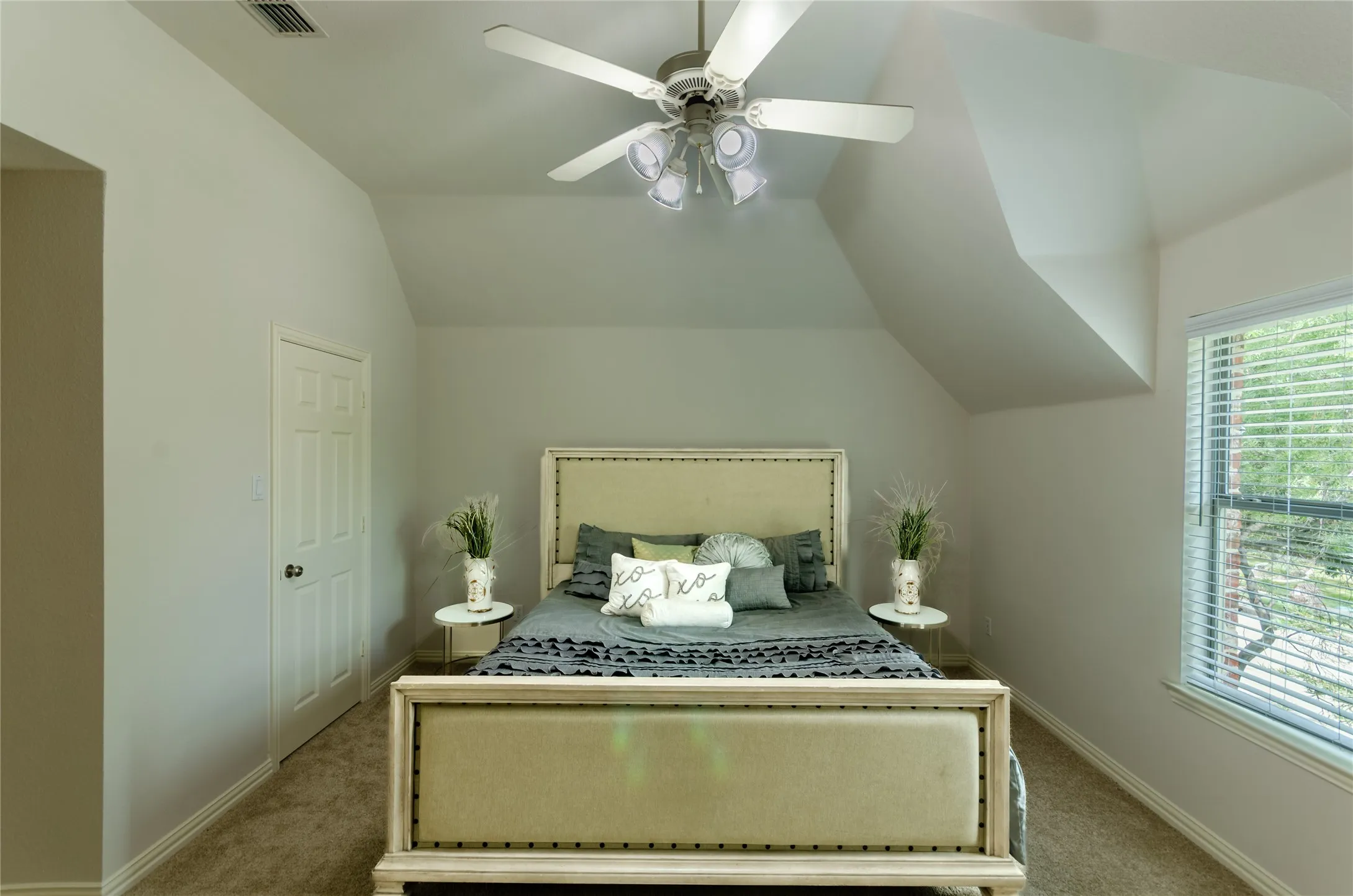 Vaulted ceilings, neutral wall color palette, carpeted flooring, window with slatted blinds, and ceiling fan with integrated light fixture