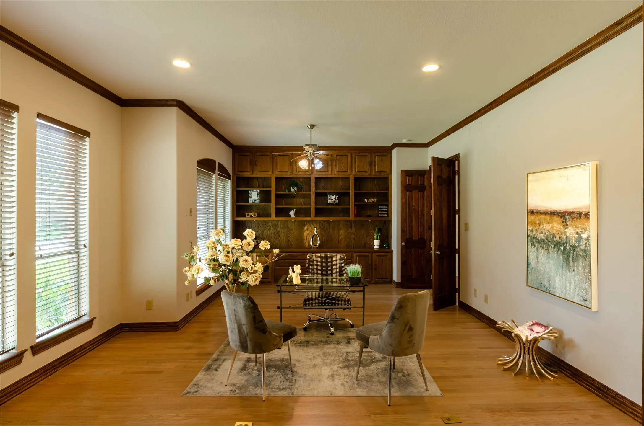 Custom wood-finish flooring, floor-to-ceiling built-in cabinetry, crown molding, and recessed lighting