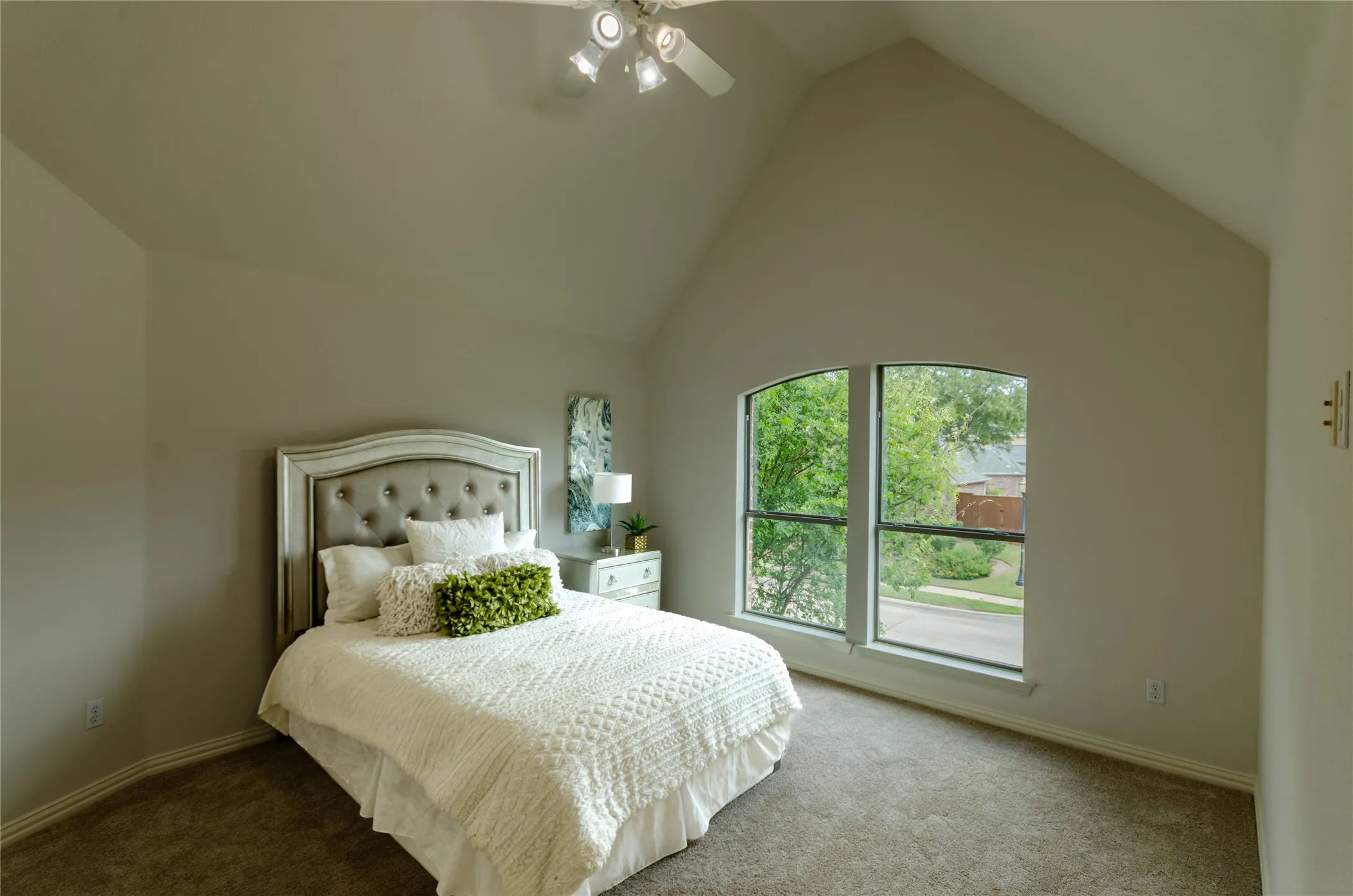 High vaulted ceiling with neutral paint, carpeted flooring, and a large arched window