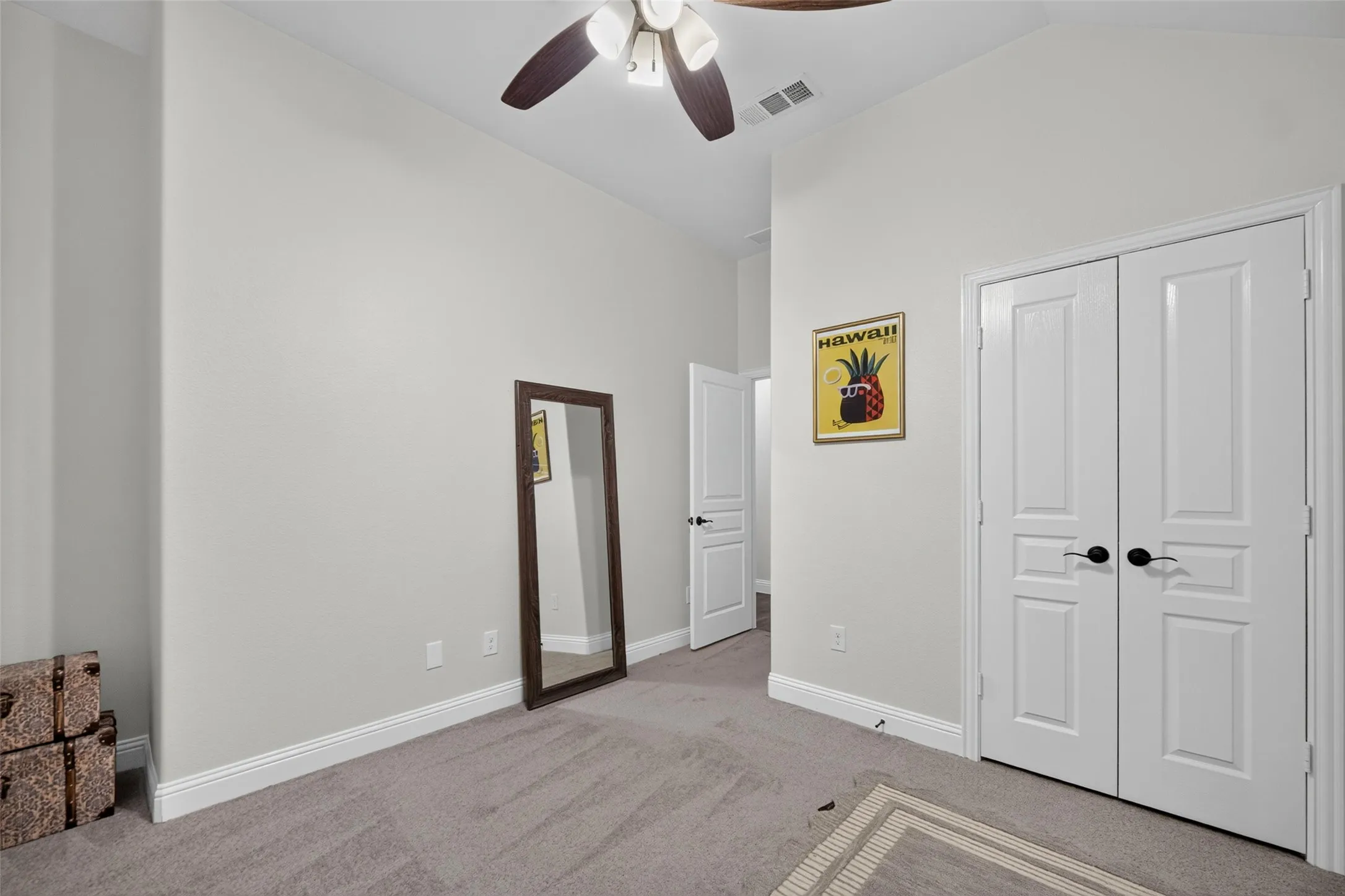 Vaulted ceilings, neutral wall tones, carpeted flooring, double-panel doors, and a ceiling fan with integrated lighting