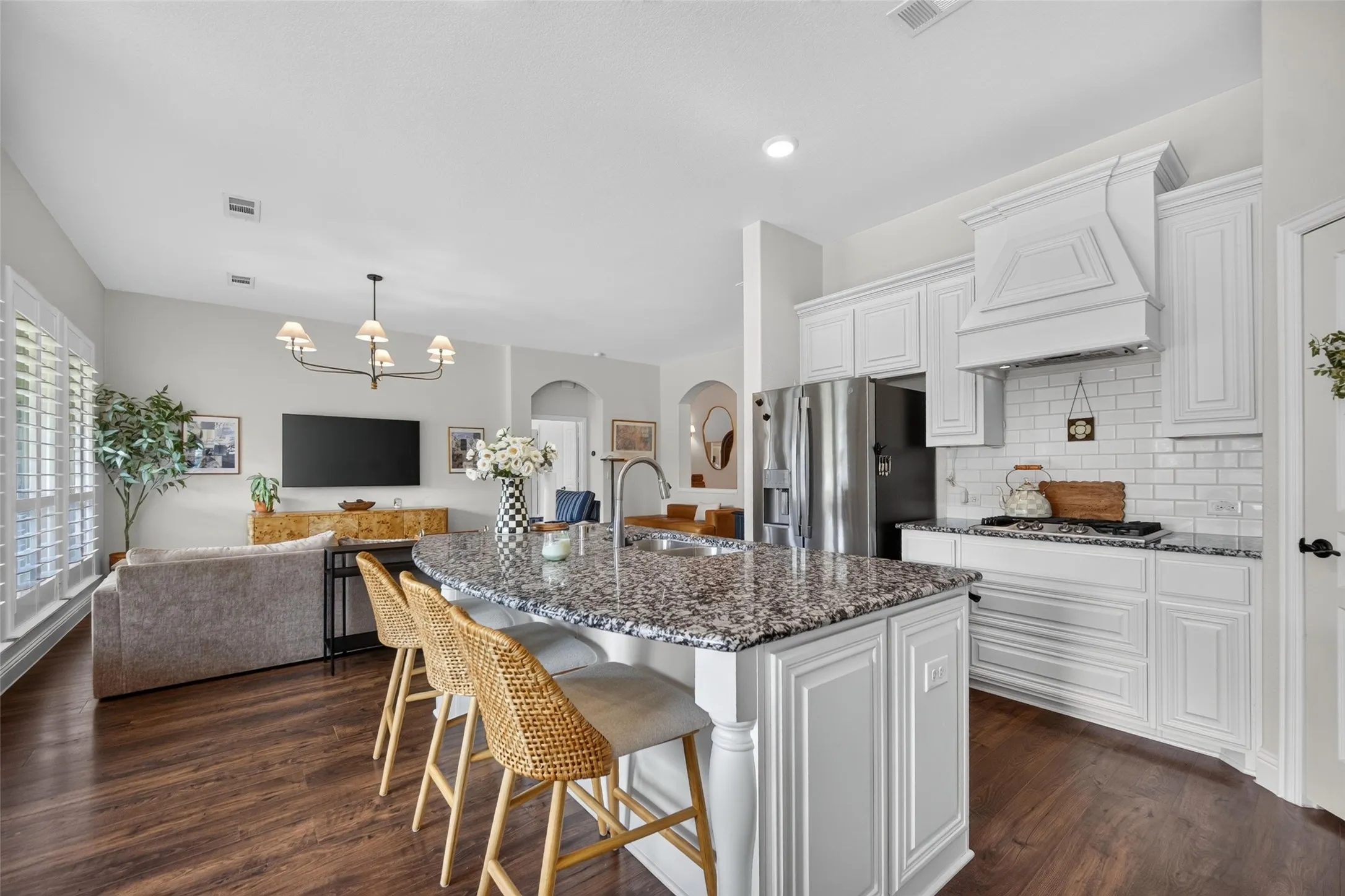 Kitchen featuring white cabinetry, a central island with a multi-tonal countertop, a subway tile backsplash, and wood-finish flooring