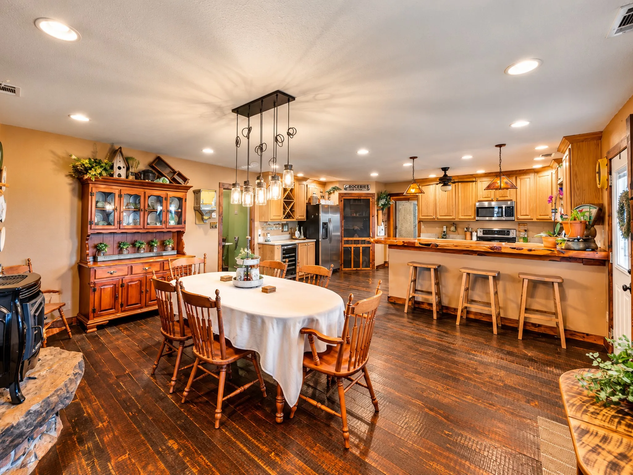 Warm wood-finish flooring complements the kitchen featuring wood cabinetry, stainless steel appliances, and a breakfast bar with wood countertop