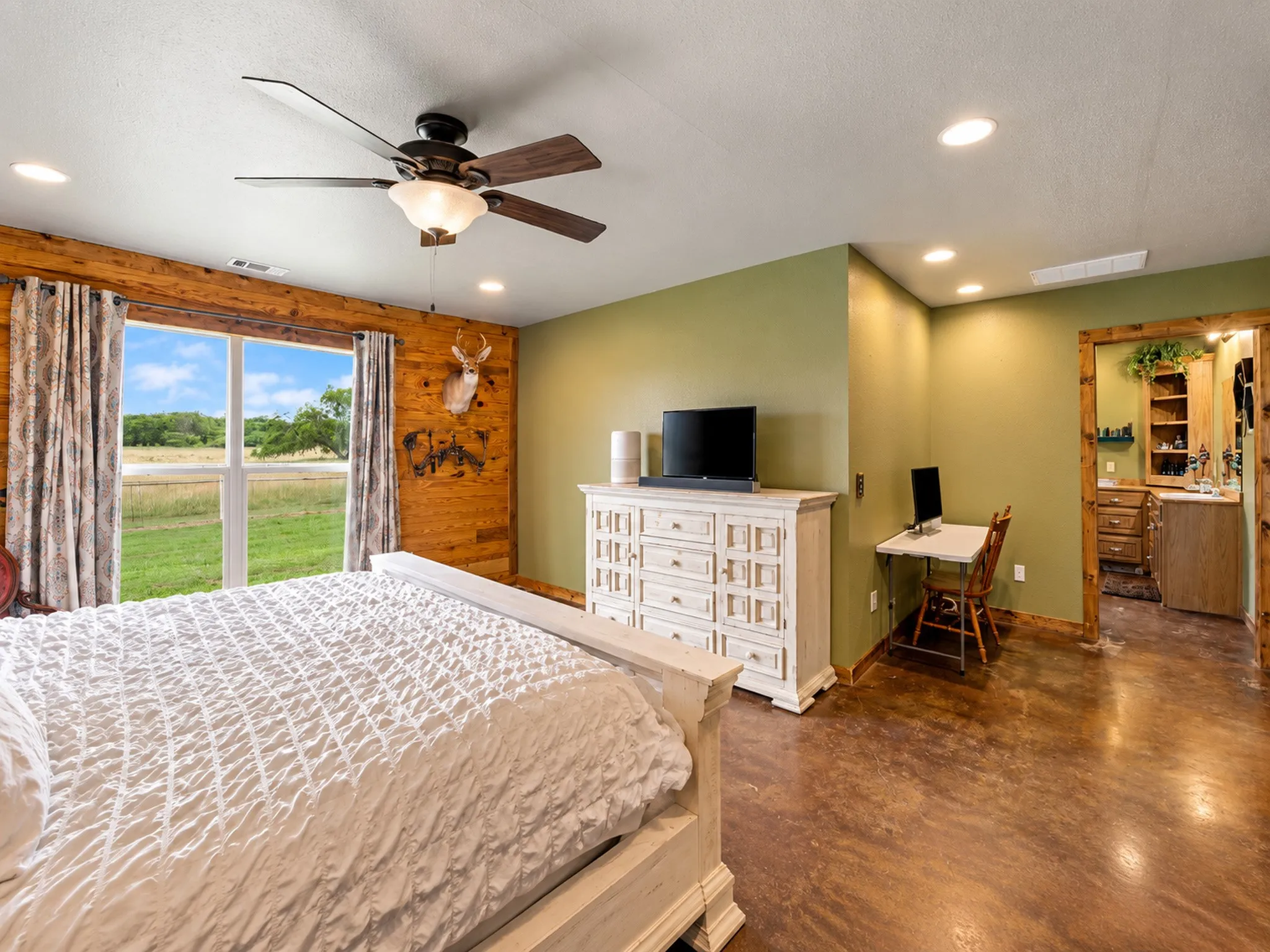 Expansive window, recessed lighting, ceiling fan, wood-finish flooring, and a natural wood-trimmed doorway