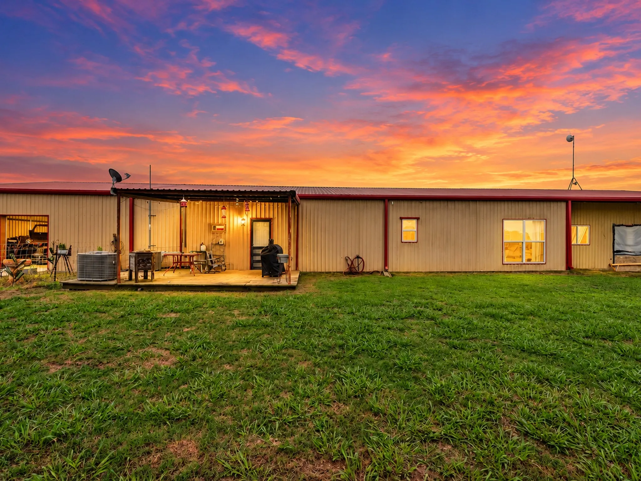 Metal-sided structure with a red trim roof and an integrated wooden deck