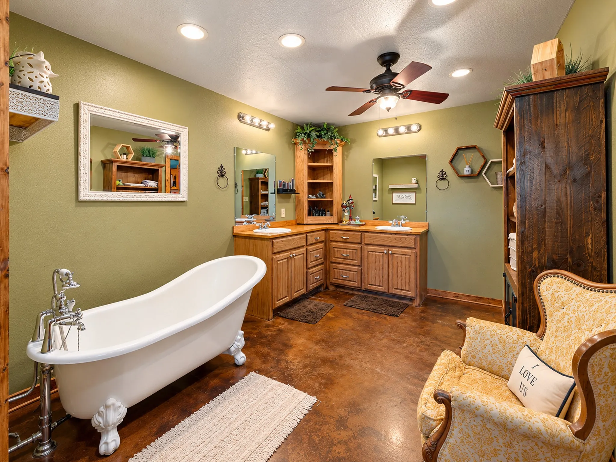 Freestanding clawfoot tub, dual vanity with wood cabinetry, ceiling fan, recessed lighting, and rich floor finish
