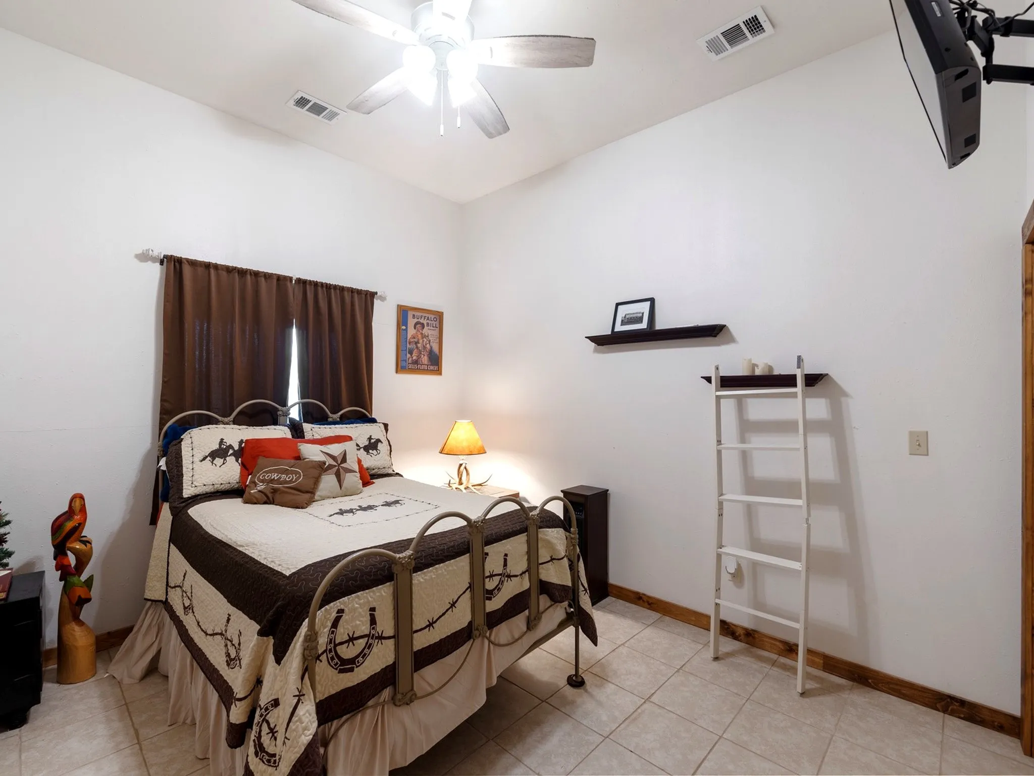 Vaulted ceilings featuring a central multi-blade ceiling fan and neutral tile flooring complemented by wood-finish trim