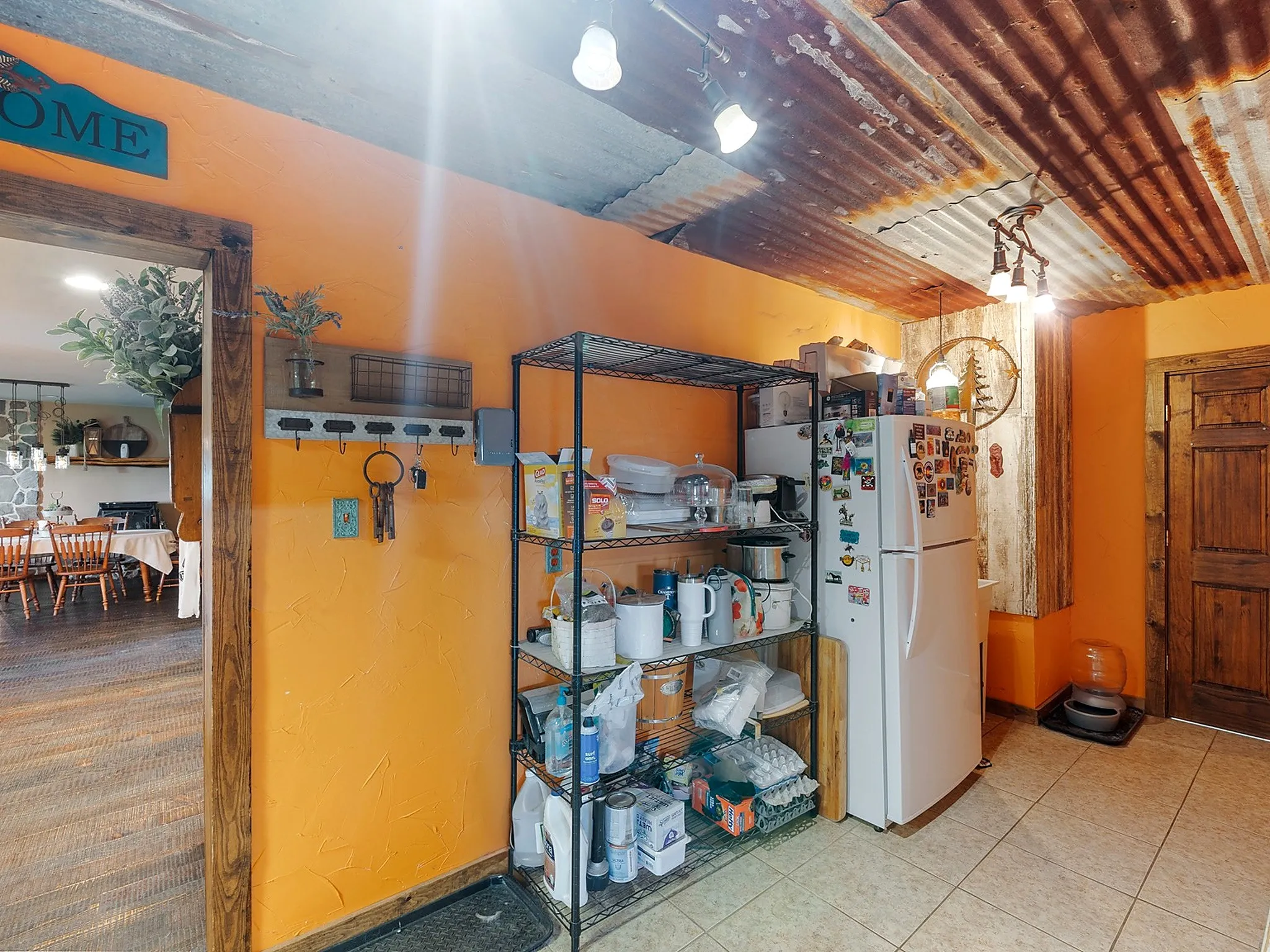 Corrugated metal ceiling featuring multi-light track lighting, textured walls, and a solid wood door with natural finish trim