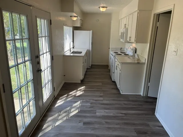 Kitchen featuring wood-finish flooring, white cabinetry, integrated appliances, and double French doors with glass panes