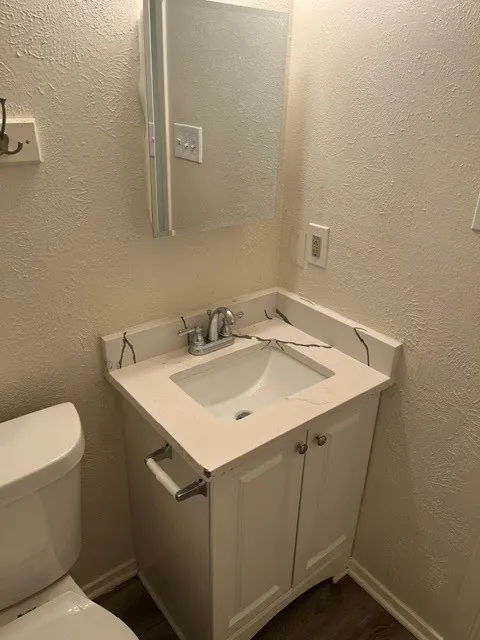 Single-sink vanity with white cabinet storage, integrated basin, stone-composite countertop with veining, chrome faucet, and mirrored medicine cabinet