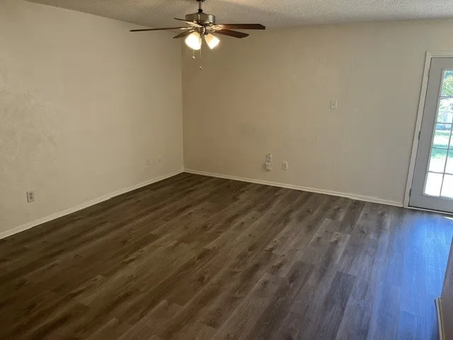 Wood-finish flooring, ceiling fan with multi-light fixture, and glass-paneled exterior door