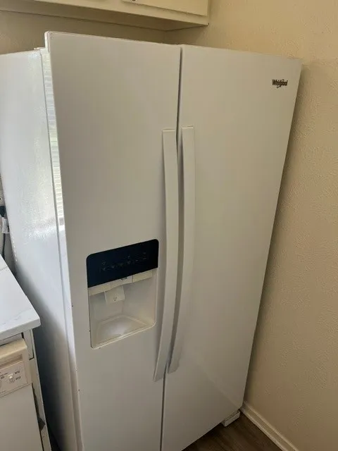 White side-by-side refrigerator featuring an integrated door-mounted ice and water dispenser
