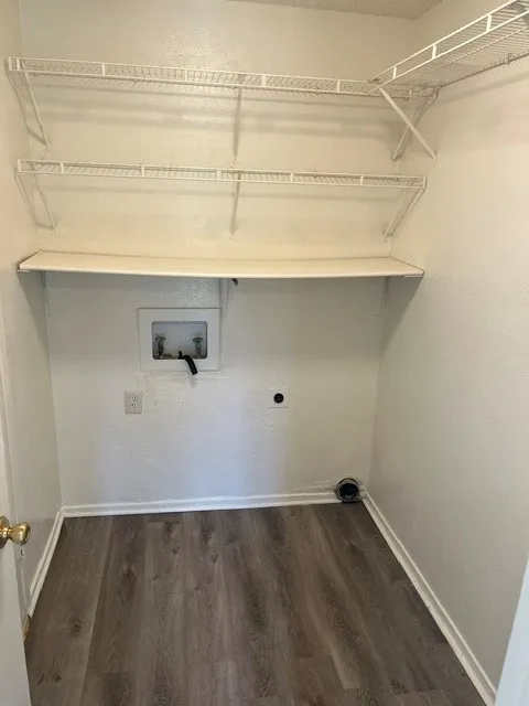 Dedicated utility area featuring wood-finish flooring, built-in tiered wire shelving, and an integrated solid surface shelf