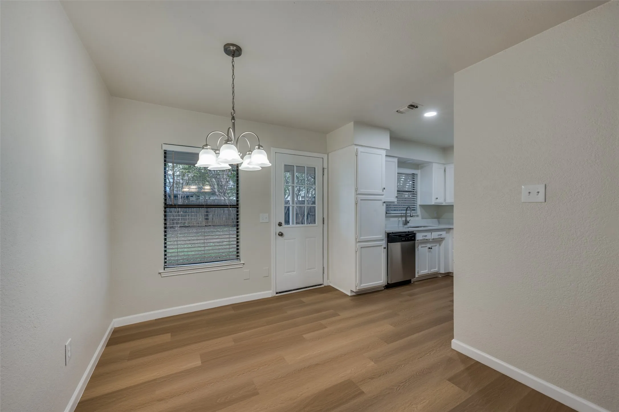 Dining area featuring wood-finish flooring, a multi-light chandelier, and access to a exterior entry door