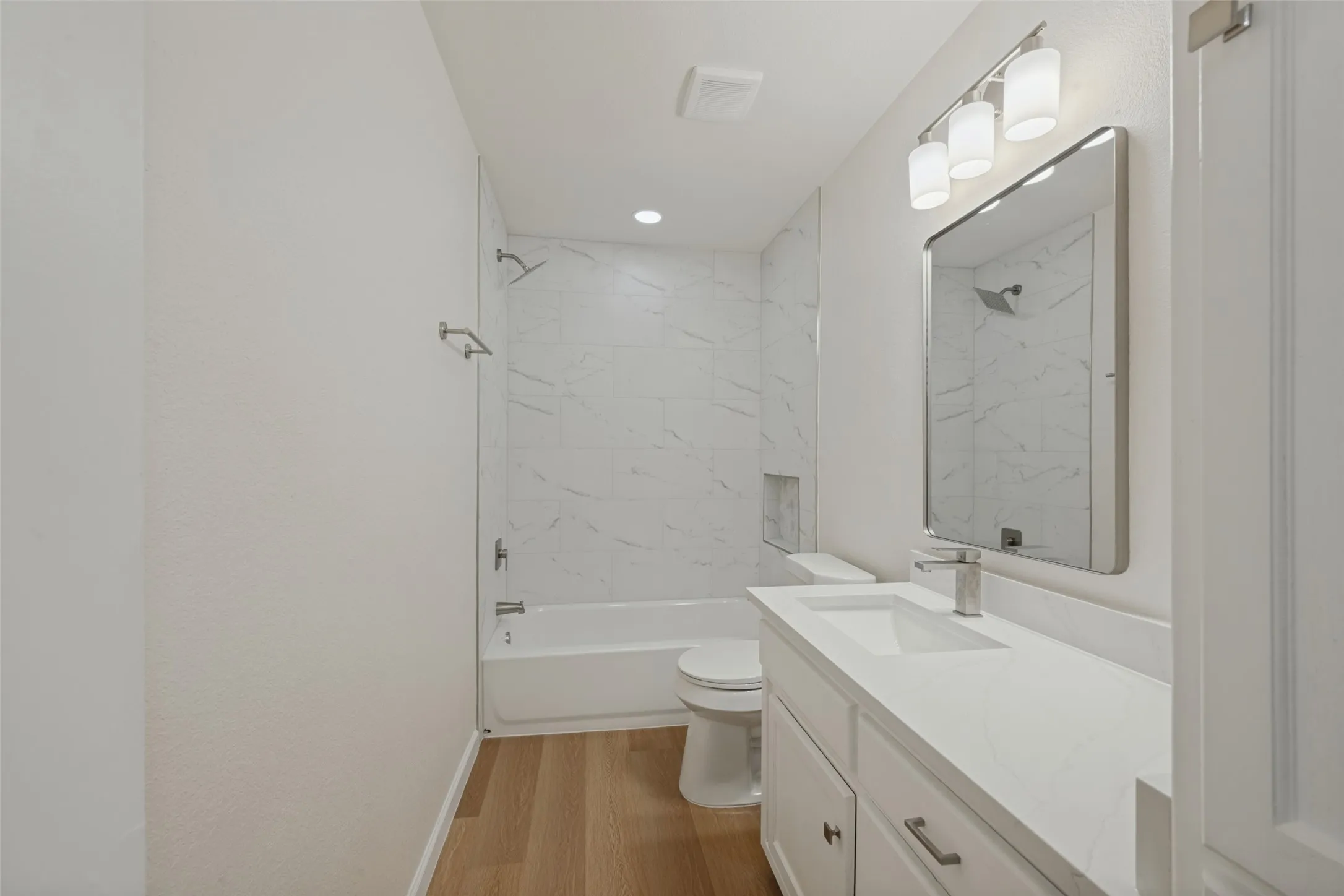Room featuring light-tone wood-finish flooring, built-in floor-to-ceiling cabinetry, a ceiling fan with integrated lighting, and horizontal window blinds