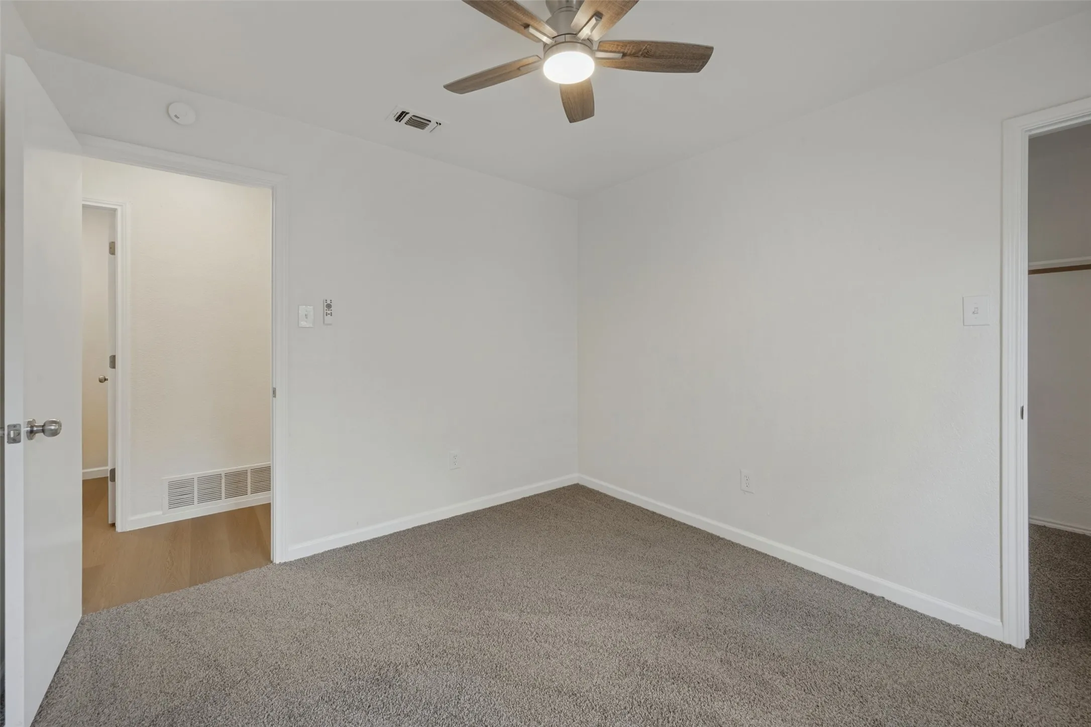 Interior space featuring wood-finish flooring, a ceiling fan with integrated lighting, dual windows, and an exterior door with a window insert