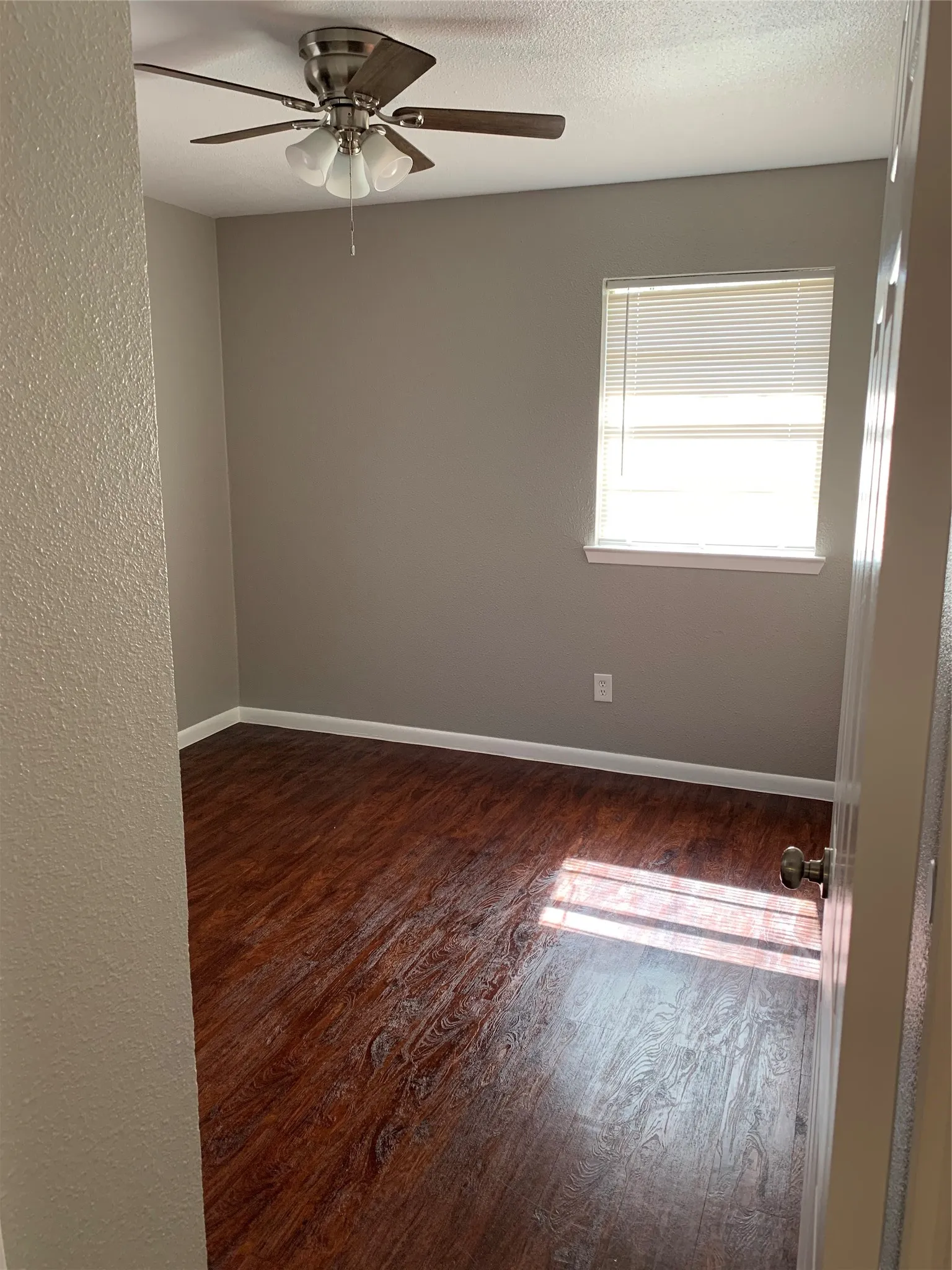 Room featuring wood-finish flooring, neutral wall paint, and a ceiling fan with integrated lighting