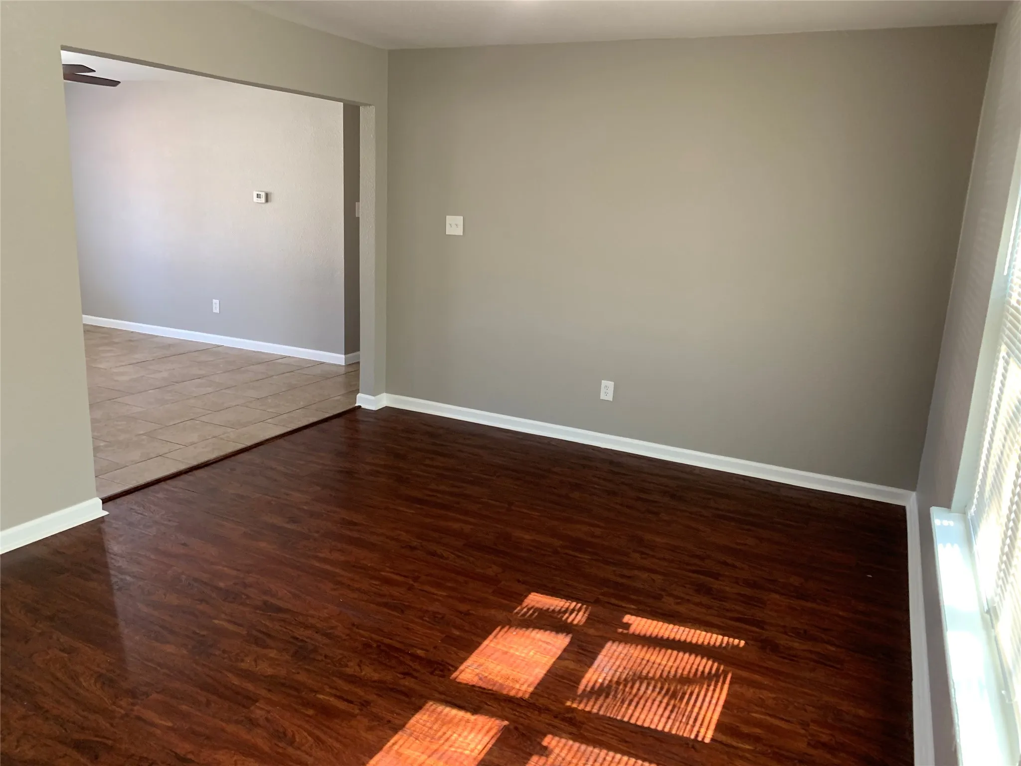 Neutral wall tones, wood-finish flooring, and light-filtering window blinds