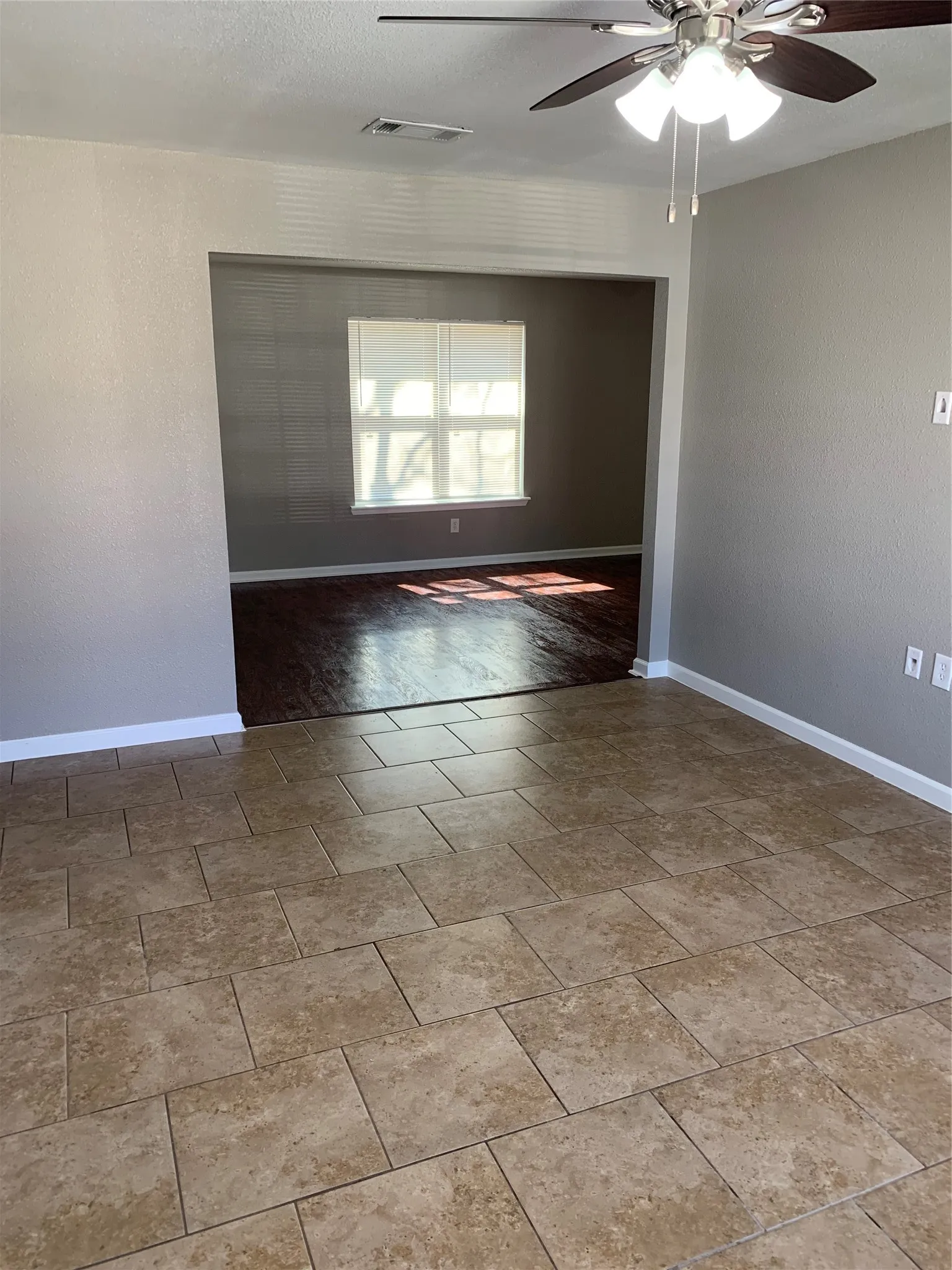 Large format ceramic tile flooring, wood-finish flooring, ceiling-mounted light fixture with fan, and multi-pane window