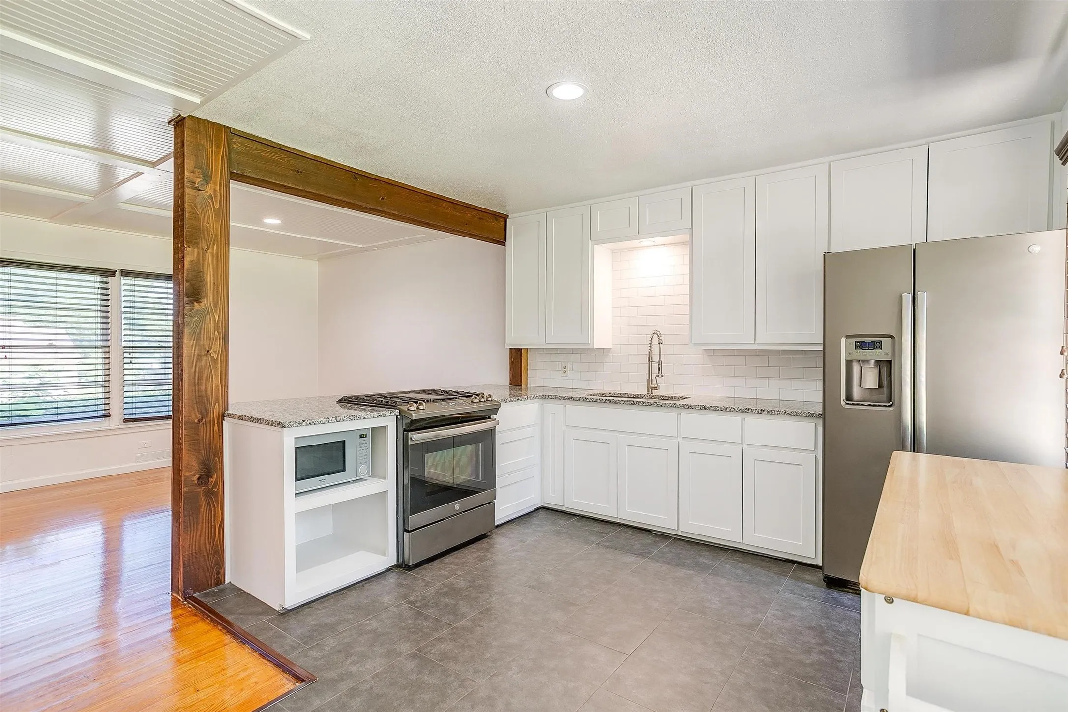 Kitchen with sink, light tile floors, white cabinetry, and appliances with stainless steel finishes