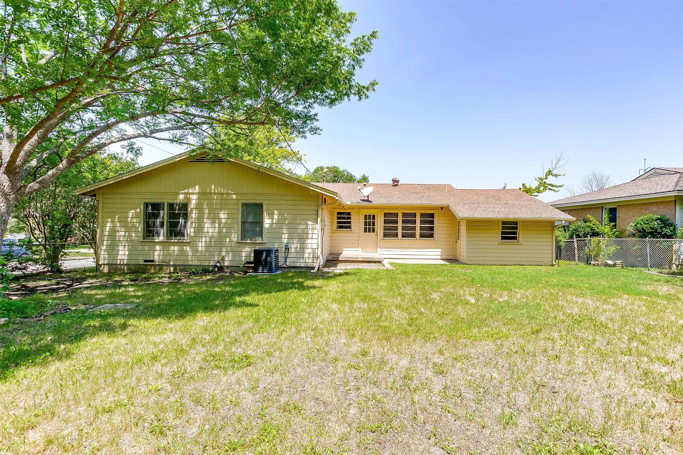 Rear view of property featuring central AC unit and a lawn