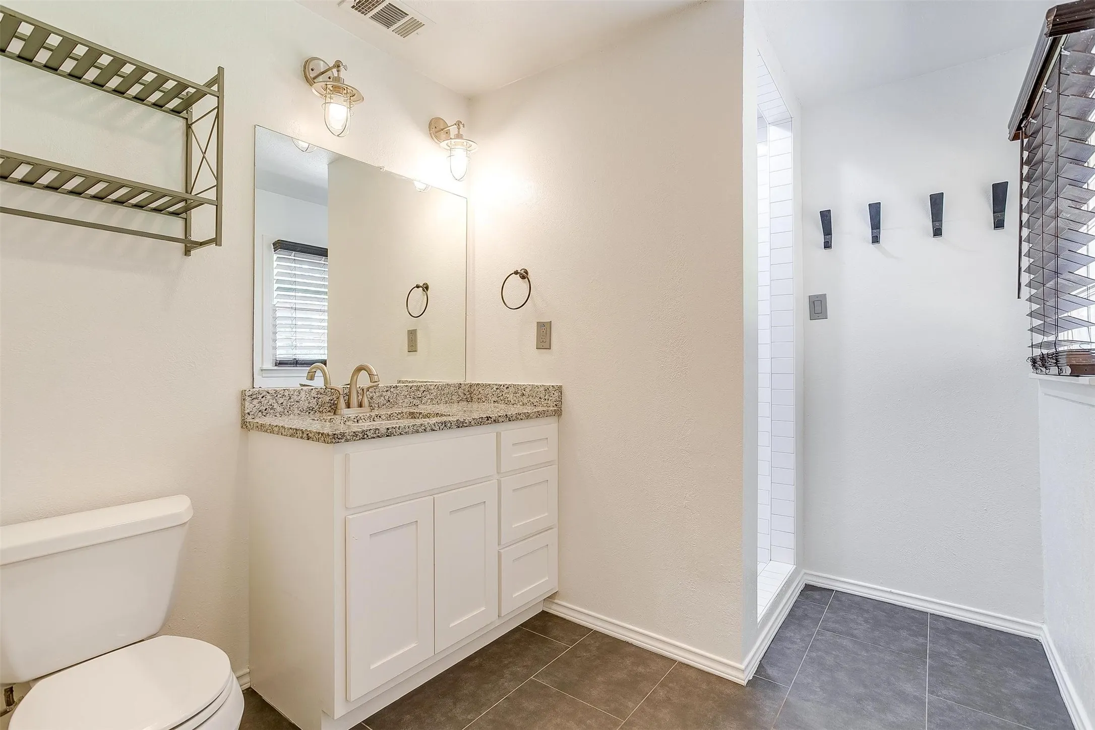 Bathroom with a shower, tile flooring, toilet, and vanity