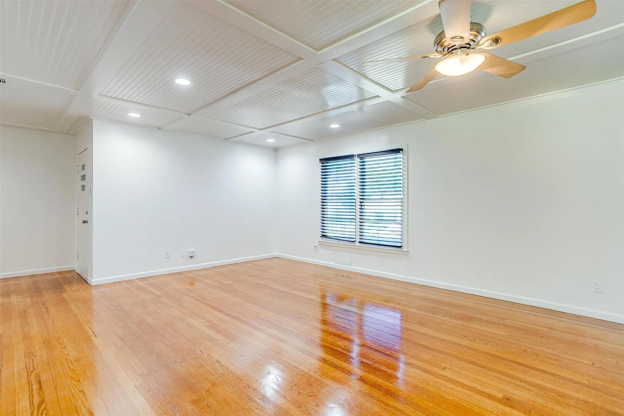 Spare room featuring coffered ceiling, light wood-type flooring, and ceiling fan