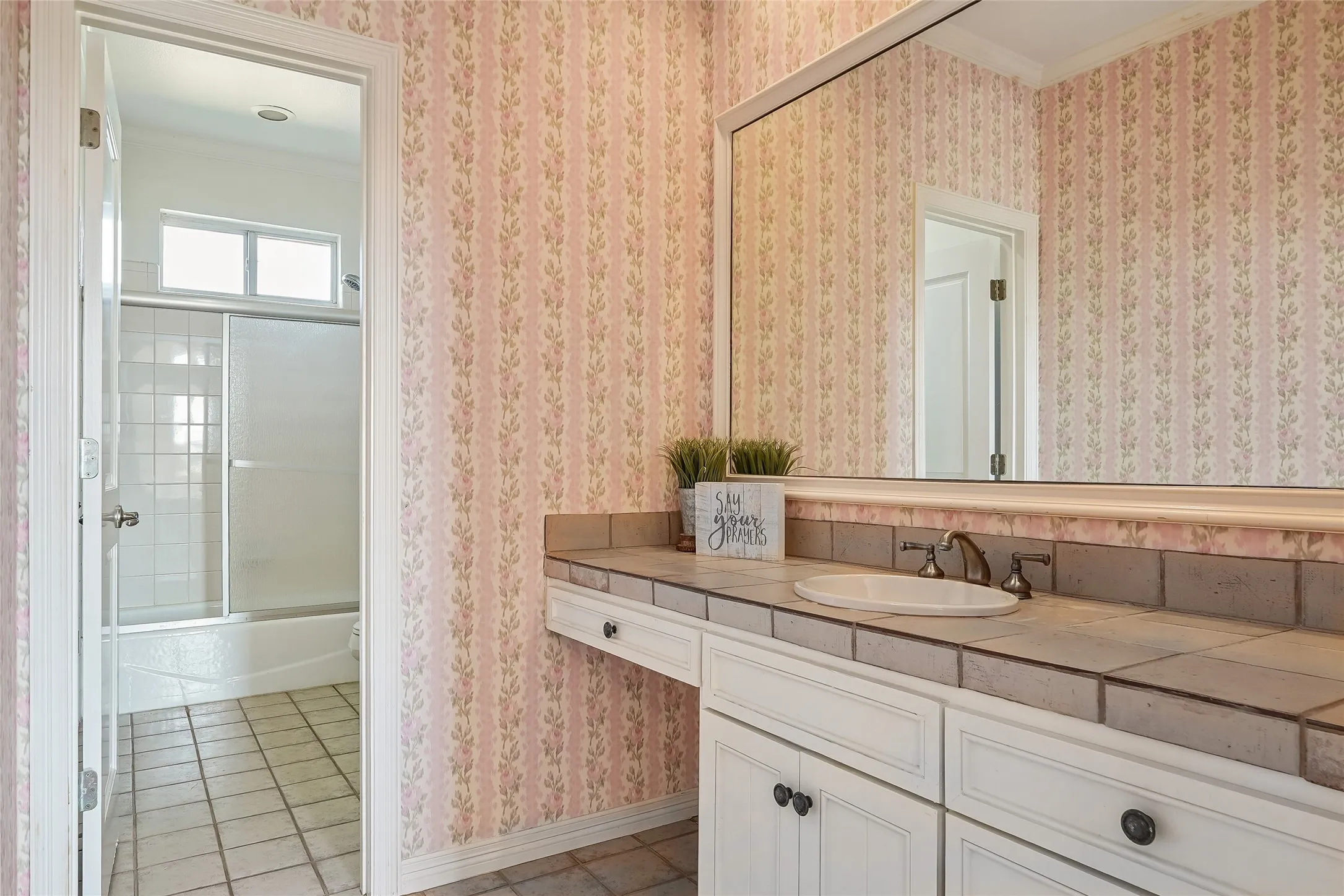 Bathroom vanity featuring white cabinetry, a tiled countertop, an integrated drop-in sink, and a large wall-mounted mirror
