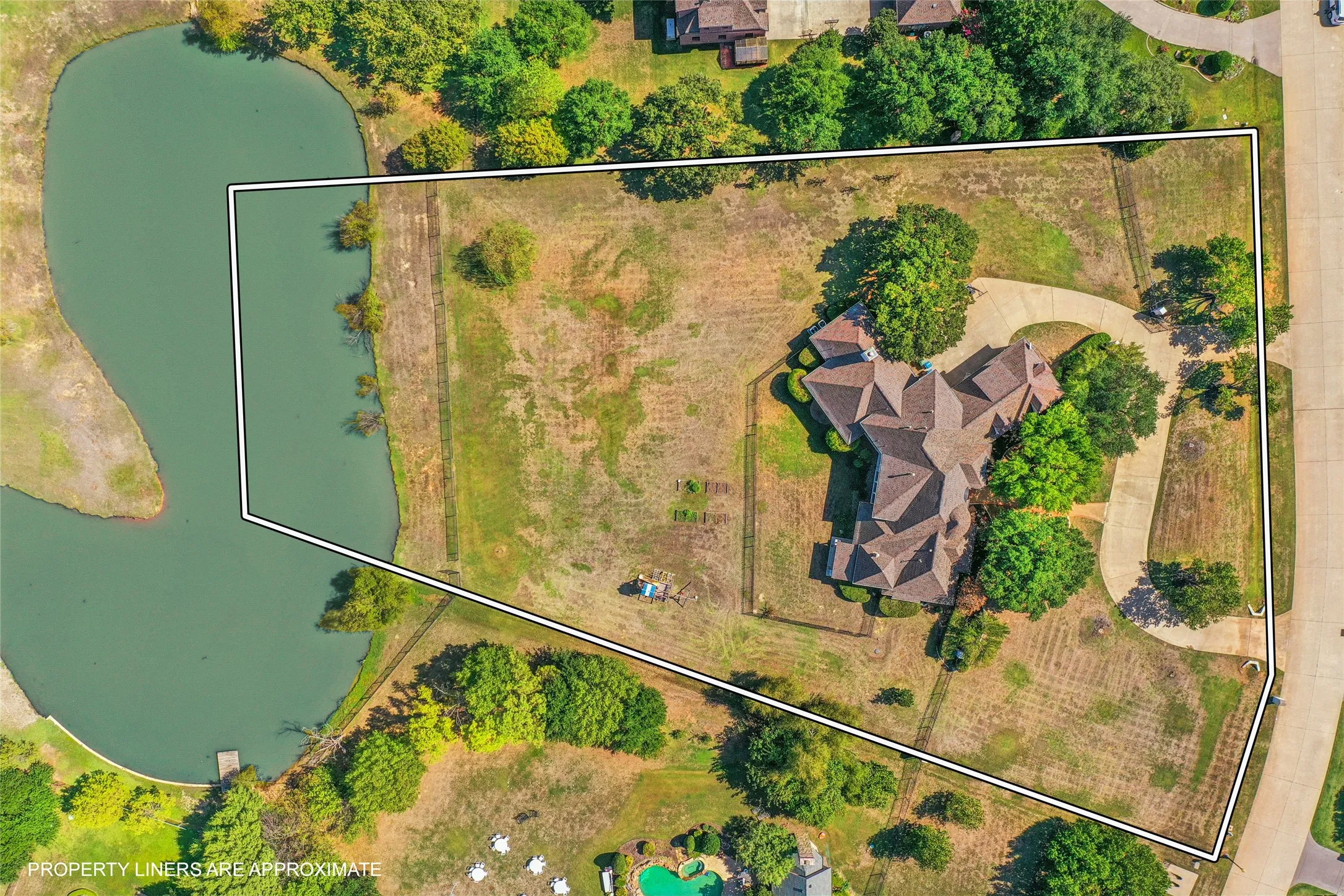 Expansive lot featuring water frontage, mature trees, a multi-pitched roofline, and a paved driveway