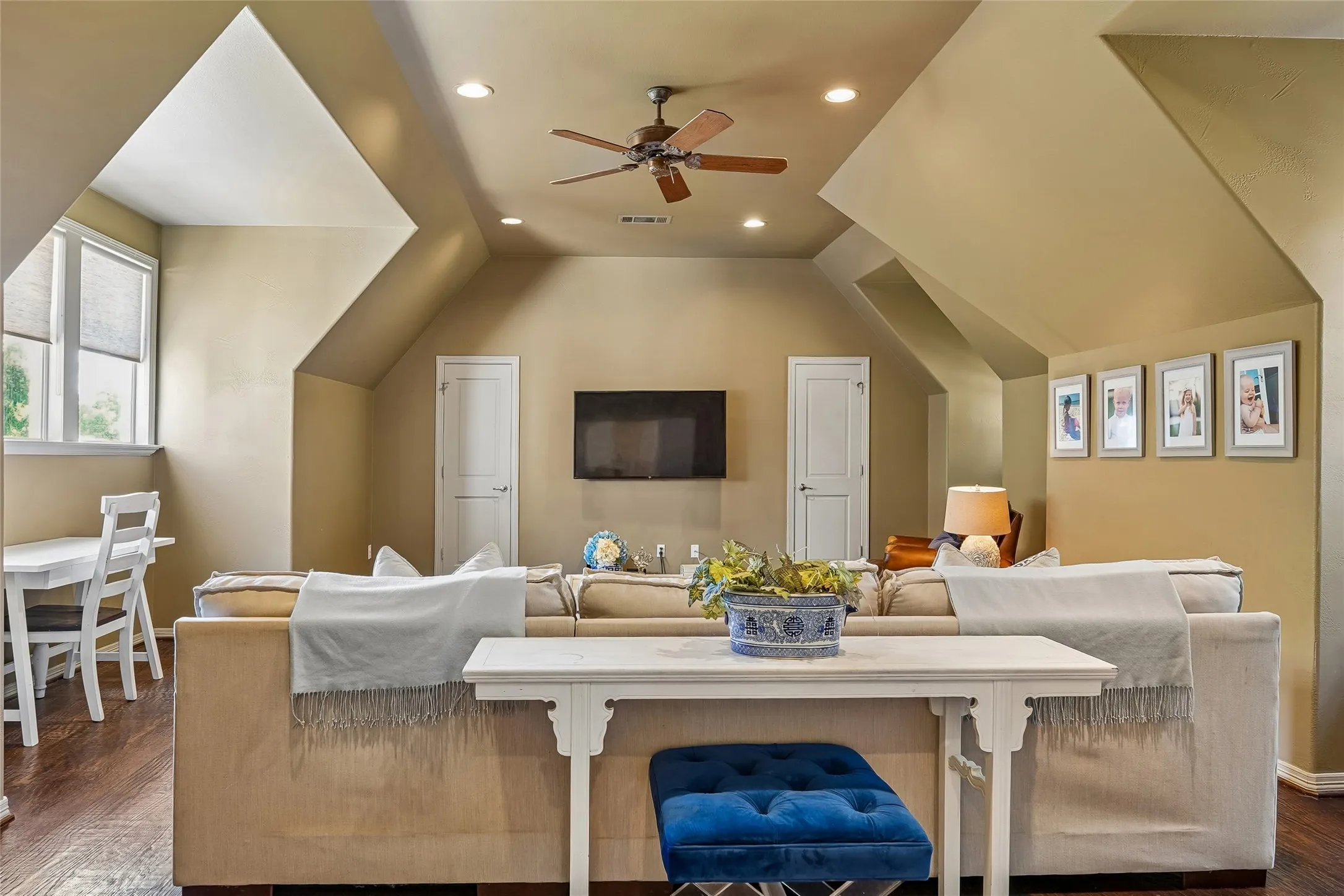 Vaulted ceiling with recessed lighting and a central ceiling fan, wood-finish flooring, and multi-pane windows