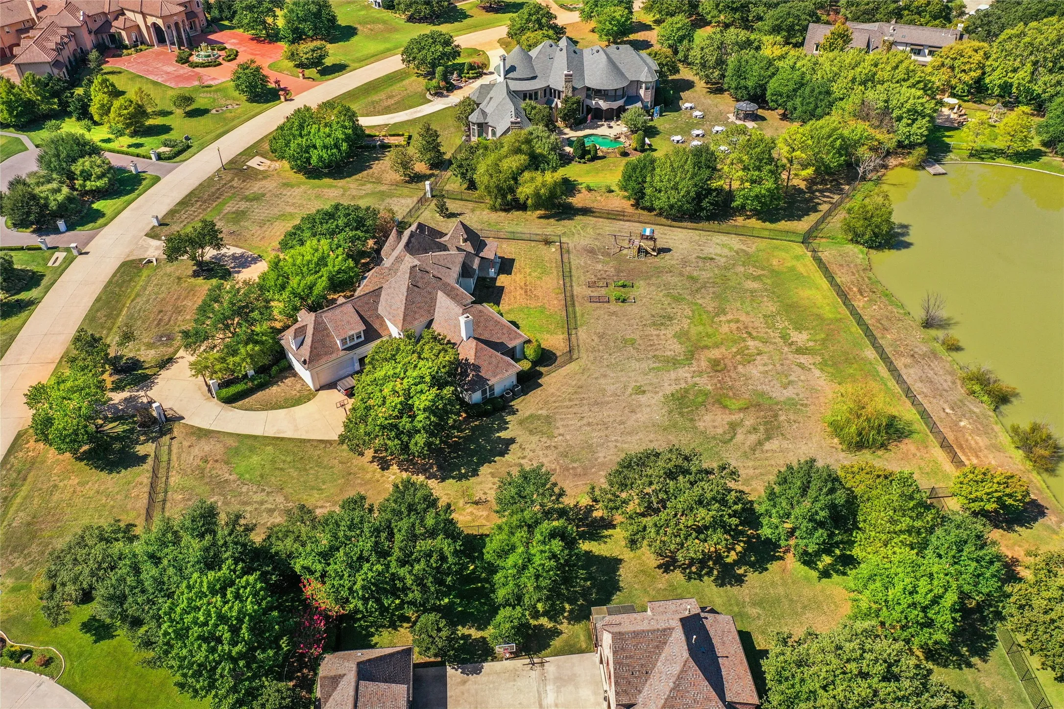 Expansive grounds featuring mature trees, a private fenced perimeter, and waterfront frontage