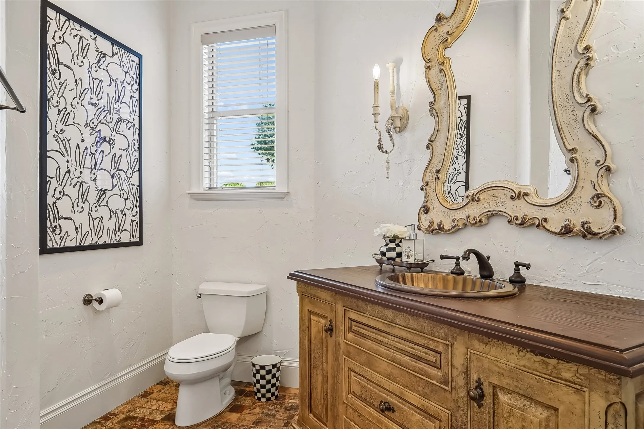 Custom vanity with wood-finish countertop, metal vessel sink, wall-mounted light fixture, and window with blinds
