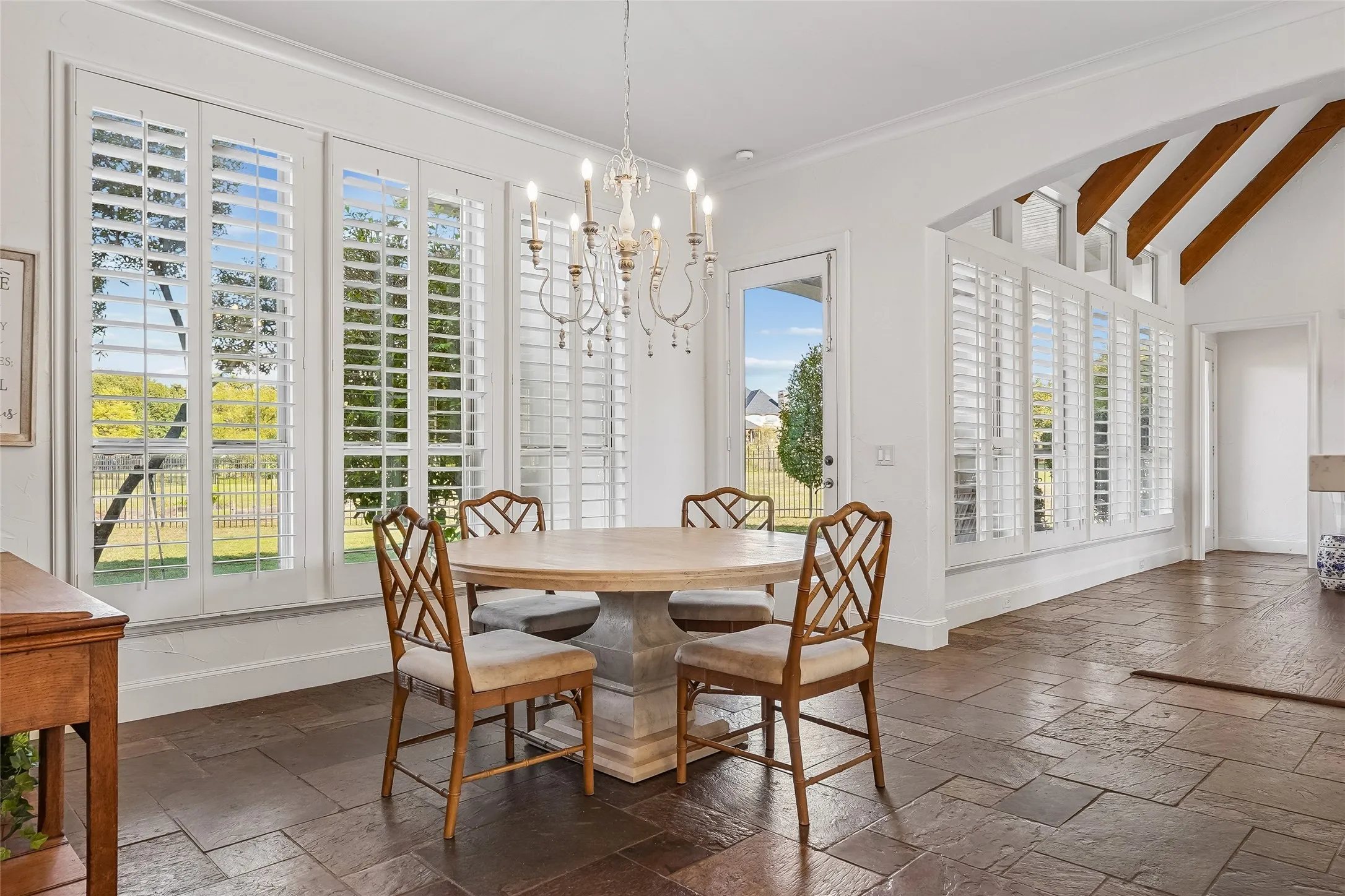 Tile flooring, vaulted ceilings with exposed wood beams, plantation shutters, and a chandelier fixture