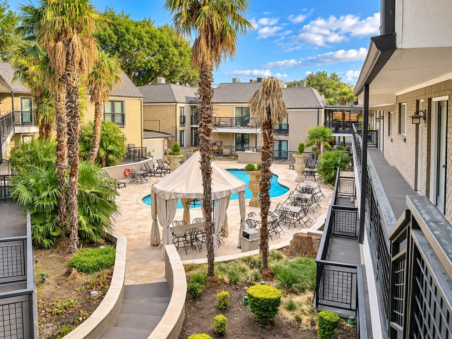Courtyard featuring an in-ground swimming pool, stone-paver hardscaping, established palm trees, and a central gazebo