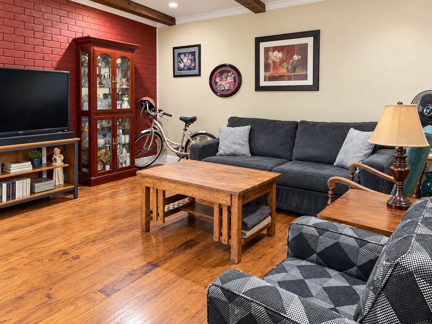 Exposed wood-finish ceiling beams, brick accent wall, and wood-finish flooring