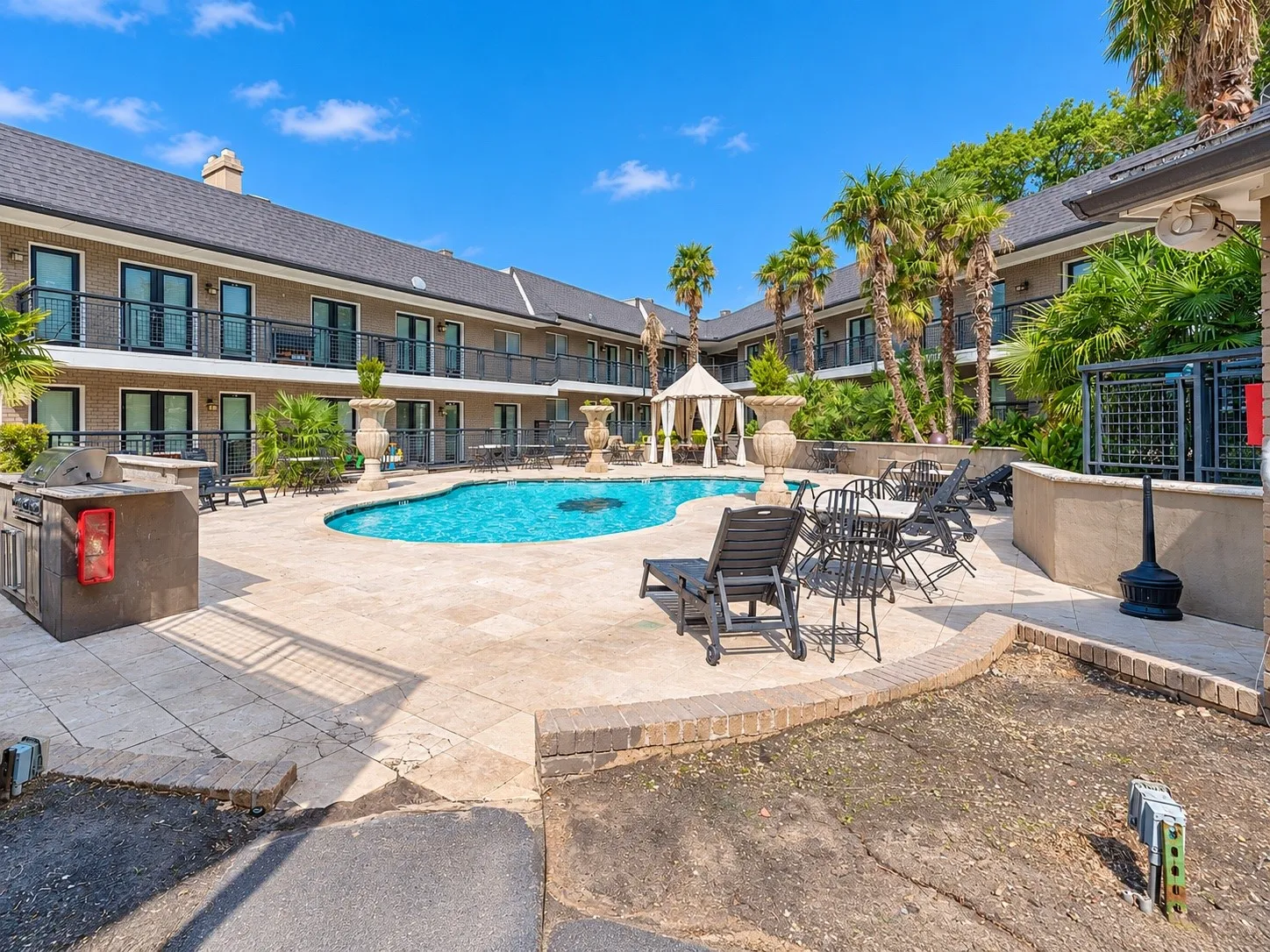 Courtyard swimming pool featuring stone-style hardscaping, built-in outdoor kitchen, pergola, and elevated balcony railings