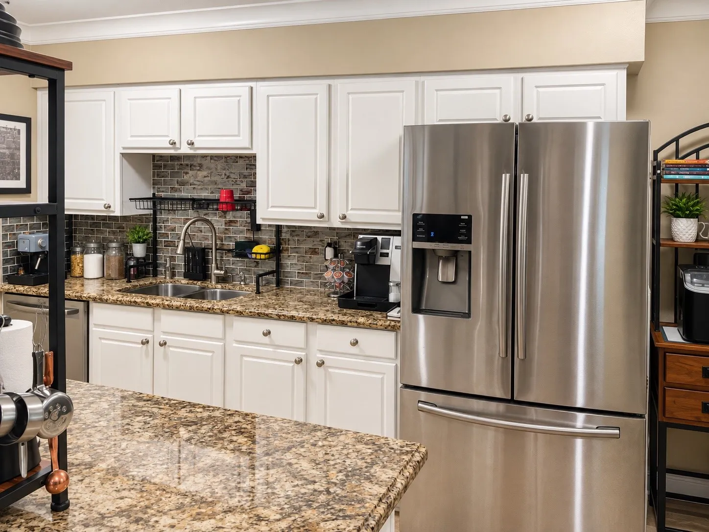 Kitchen featuring white cabinetry, stone-surface countertops, a stainless steel refrigerator, and a brick-finish backsplash