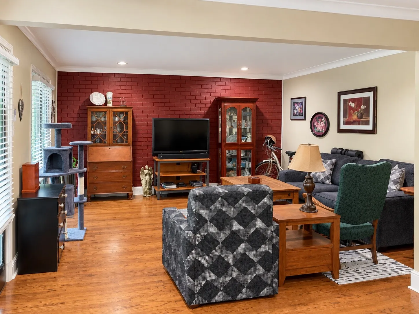 Interior space featuring wood-finish flooring, a red-painted brick accent wall, recessed lighting, and crown molding