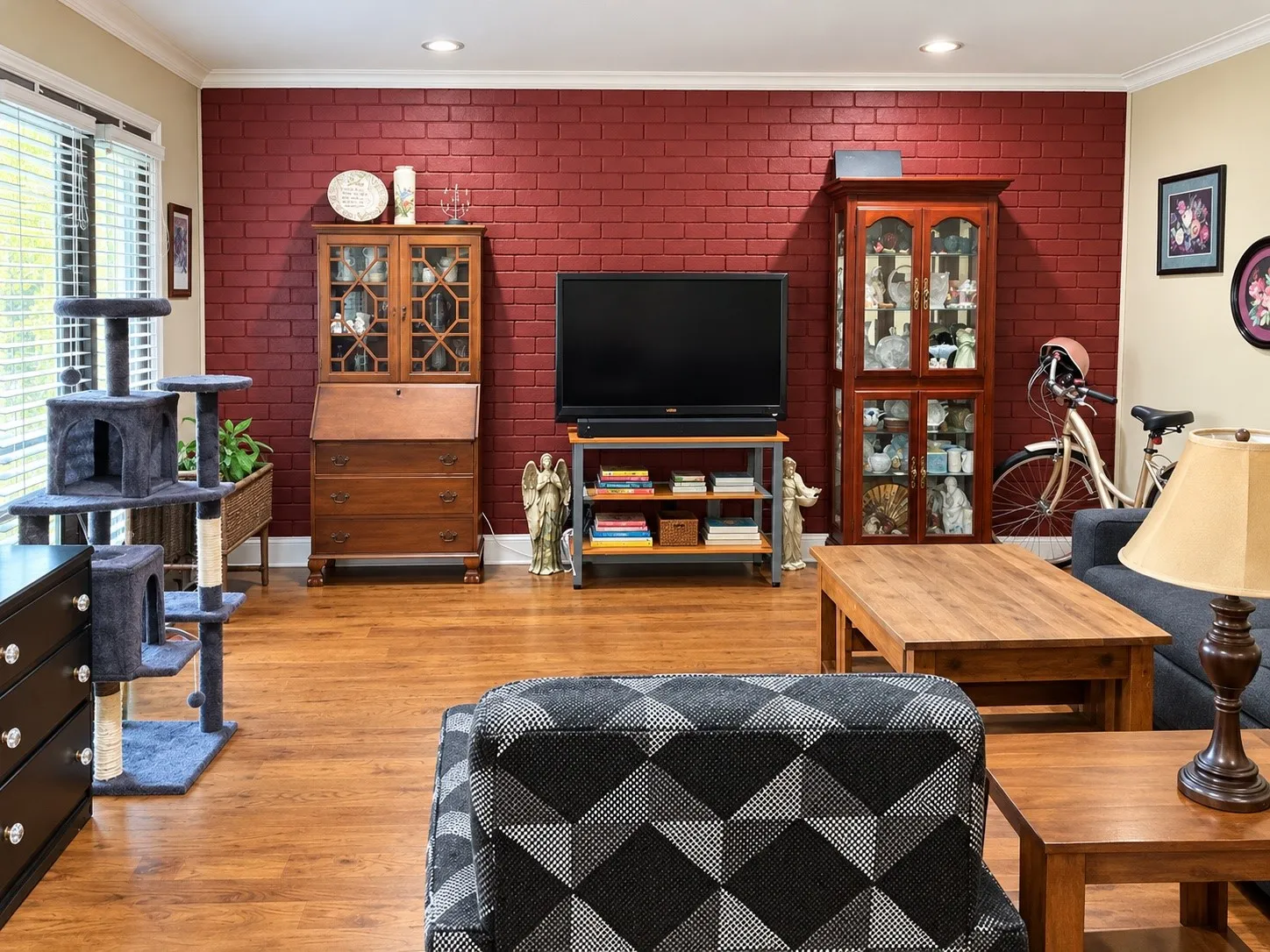 Red brick accent wall, wood-finish flooring, and recessed ceiling lighting