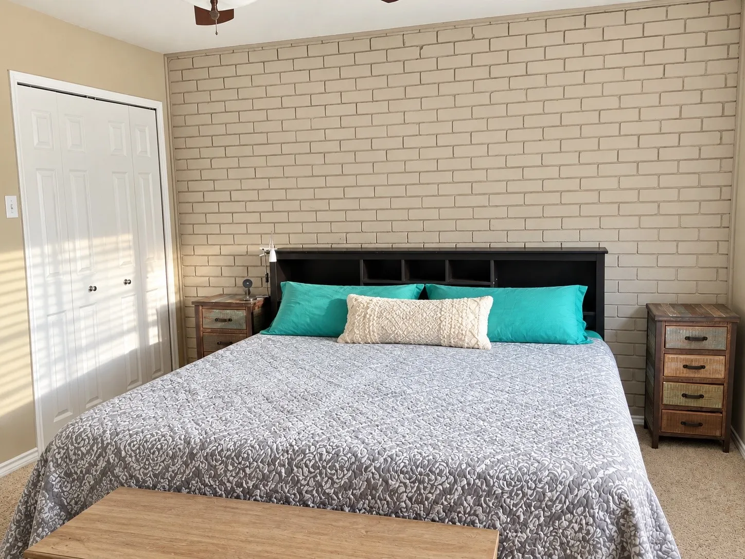 Accent wall featuring painted brick masonry and double-door closet with paneled detailing