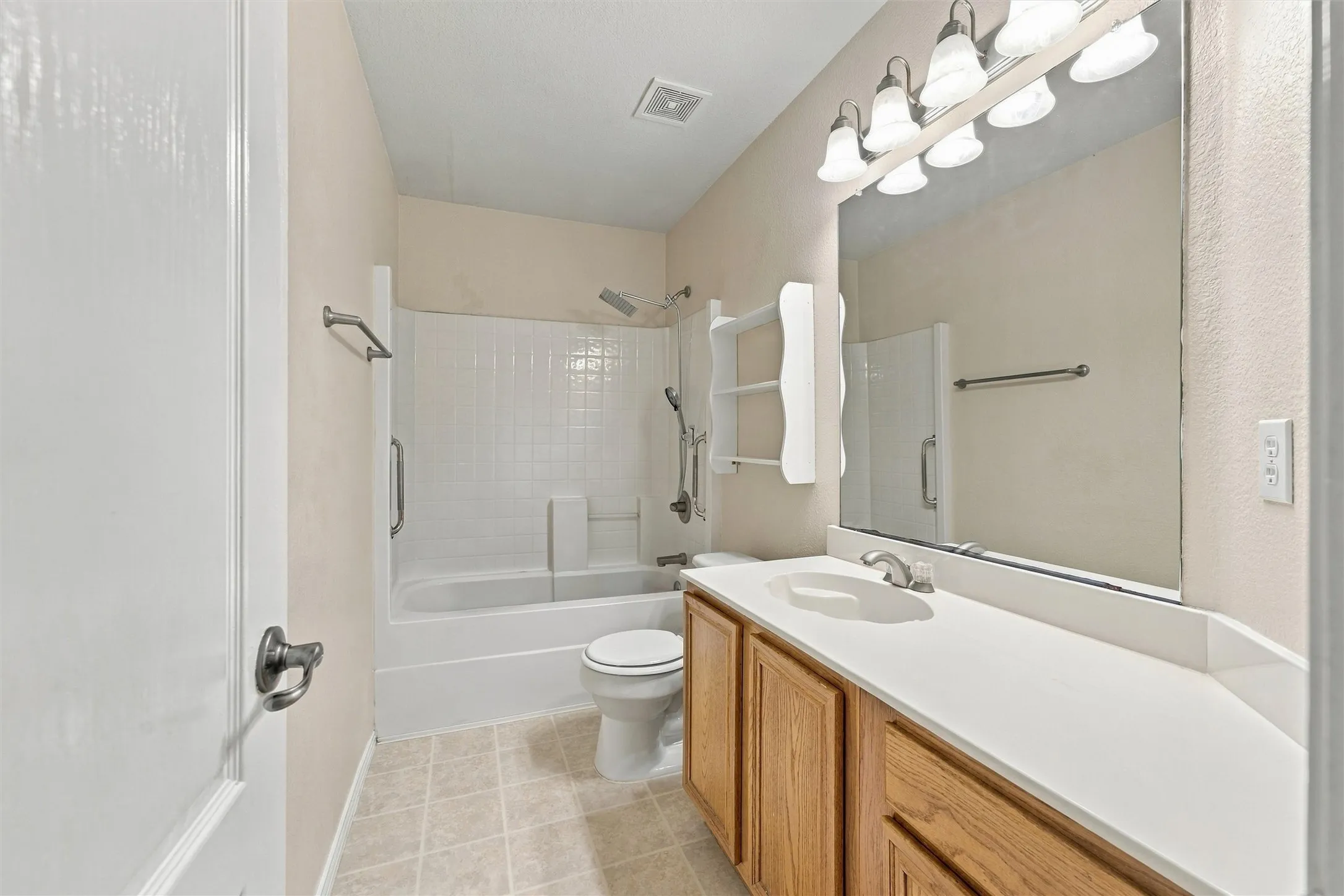Bathroom featuring a composite countertop with integrated sink, wood-finish vanity cabinetry, full-width mirror, five-light fixture, and a tile-surround tub and shower combination
